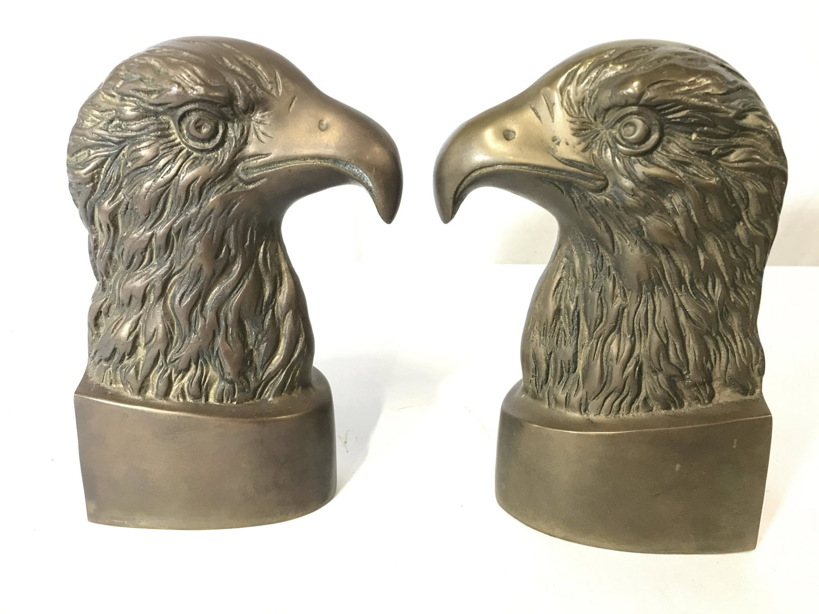 Pair Vintage Gold Toned Brass Eagle Head Bookends: Lot includes 2 bookends. Each are gold toned and brass. Each depict an eagle head. Both measures approx 9 inches tall 4.5 inches deep 3 inches wide. Bookends, bird bookends, Eagle bookends, brass book