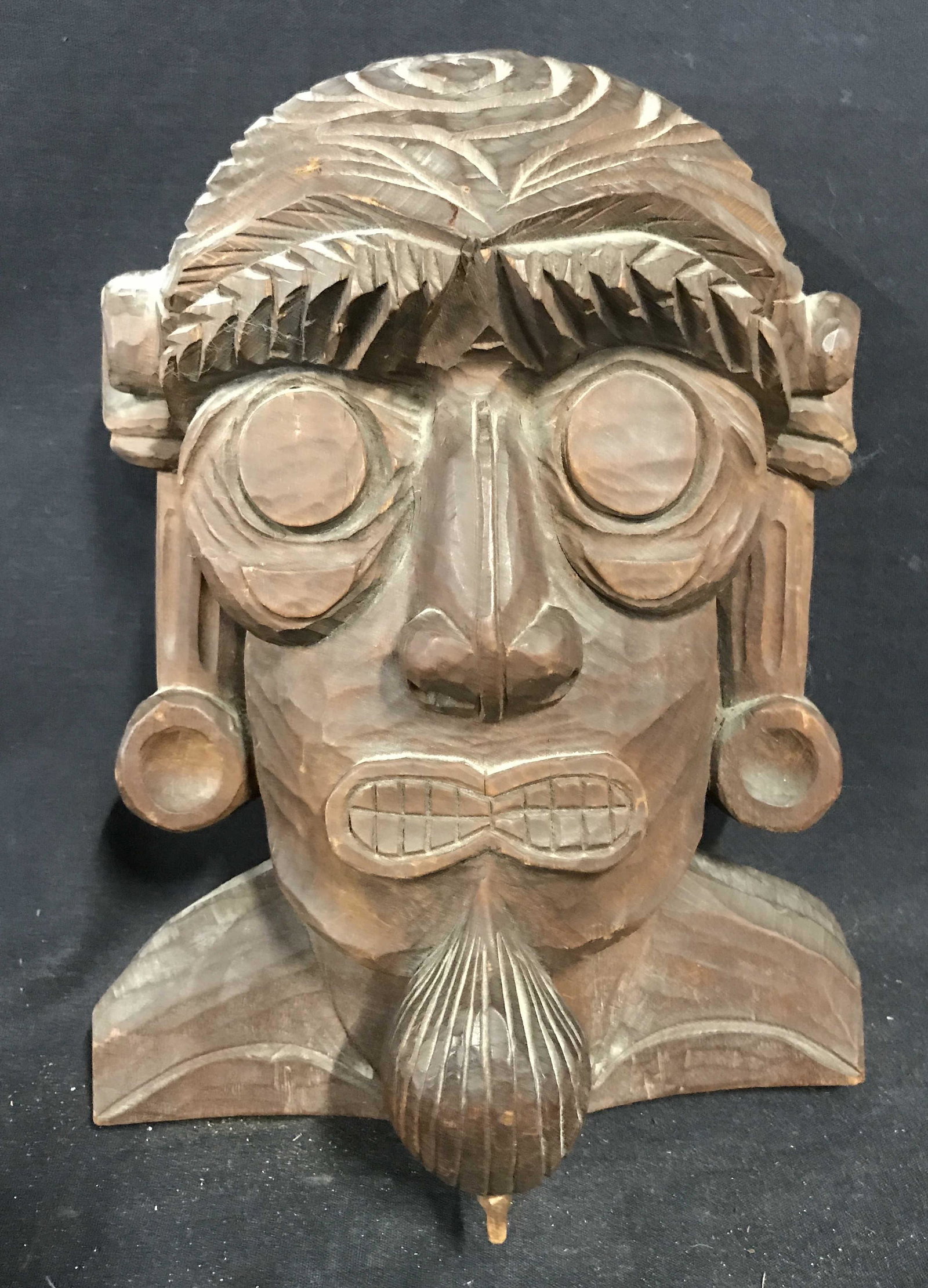 Signed Japanese Wood Carving Bust: Signed Japanese wood carving bust, signature to the back in Japanese, subject a A bust of a stylized male face, face has beard long earrings and wide eyes, measures 11 inches tall by 8 inches wide, st