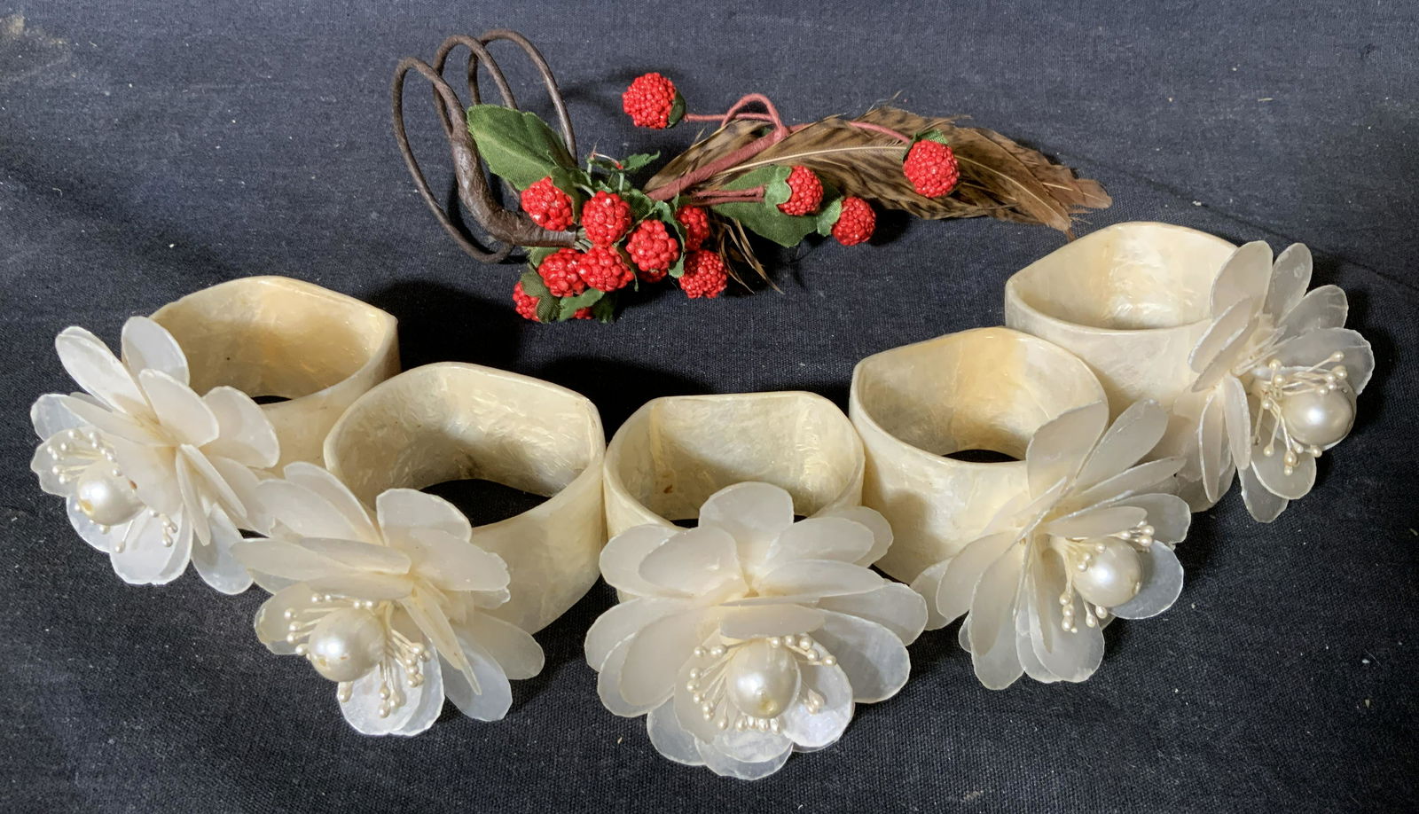Group Lot 6 Napkin Rings: Group Lot 6 Napkin rings, 5 of 6 are made of a thin possibly shell material with flowers to the top, one of the six is made to appear as twisted vines with feathers and red berries, largest one measur