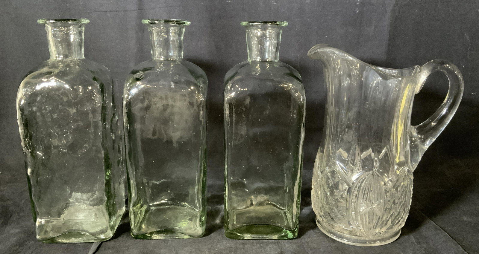 Lot 4 Glass Vessels and Pitcher: Lot 4 Glass Vessels and Pitcher, no apparent inscriptions or marks, pitcher measures 9 3/4 inches tall x 7 1/2 inches at widest point, jugs measure 11 x 4 inches at widest point, some surface wear to 