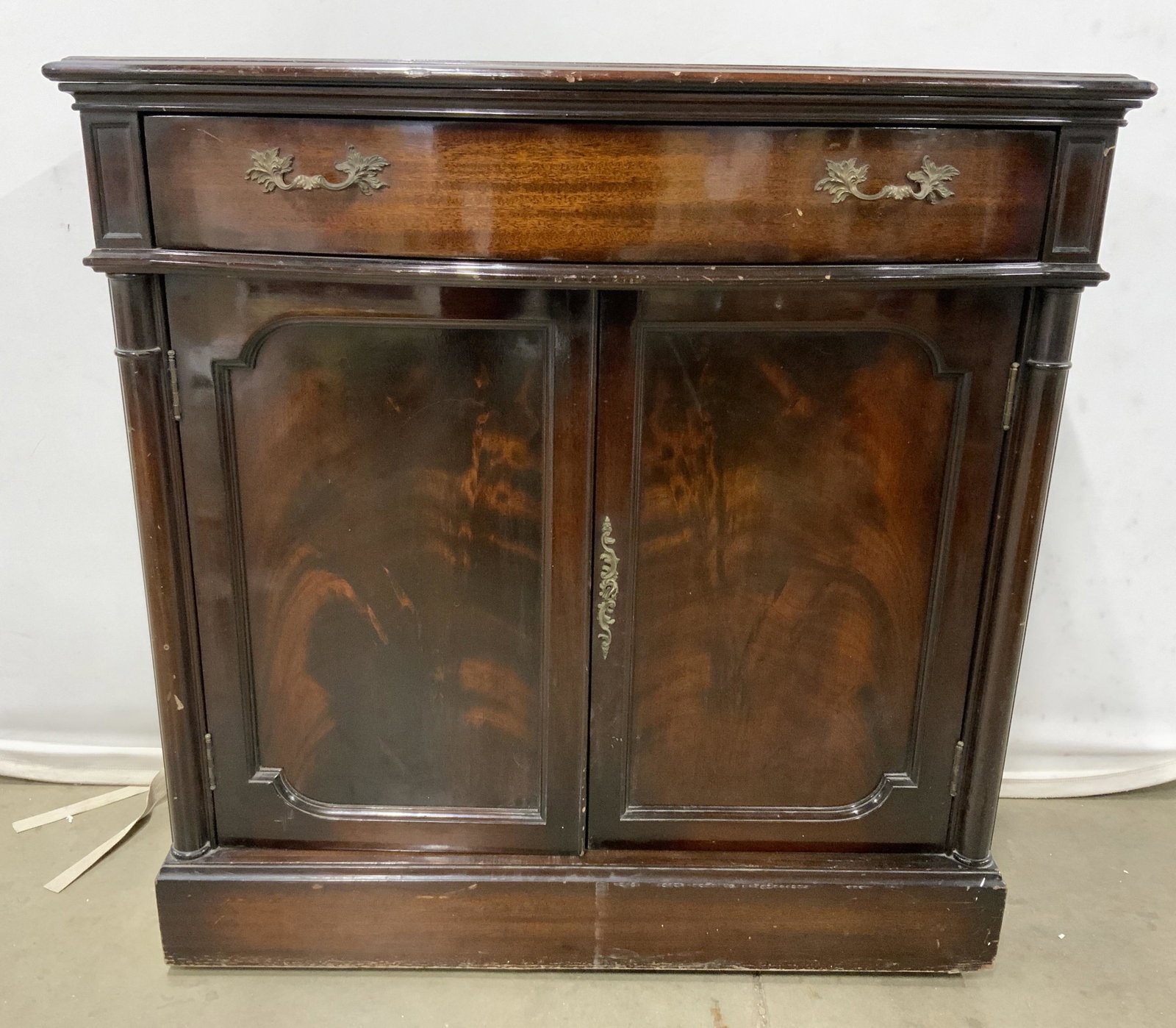 BAR MART Vintage Bar Cabinet On Wheels: Backside has tag which reads BAR MART 62 WEST 45TH ST NEW YORK. Bar Cabinet is vintage possibly antique. Piece is brown toned and wooden. Top of piece has 1 drawer with gold toned brass handles. Piece