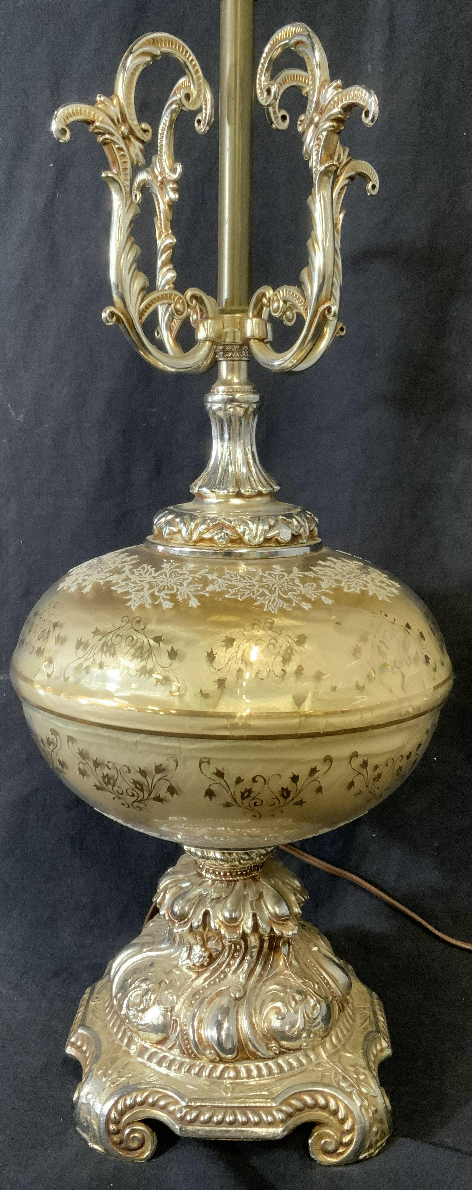 Baroque Style Tabletop Lamp: Baroque style table top lamp, possibly vintage. Body is glass, base and neck are metal, decorated with cast detailing. Body is decorated with a floral pattern gold tone striations also decorate body. 