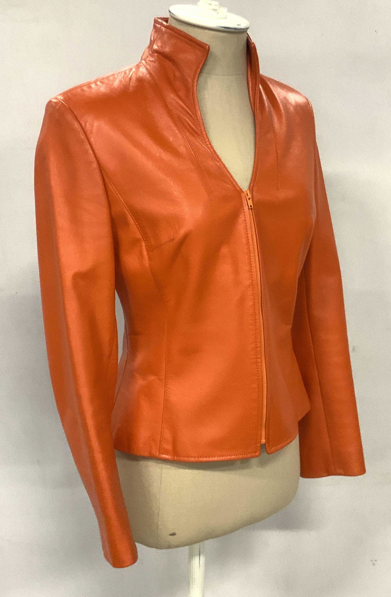 JOY PHILBIN Orange Leather Style Zippered Jacket: An orange leather style zipper jacket one worn by Joy Philbin. Interior of the jacket is partially lined with a soft hand textile. Approx. Size Small. Approx. Length 20 in. Bust approx. 32.5 in. Jacke