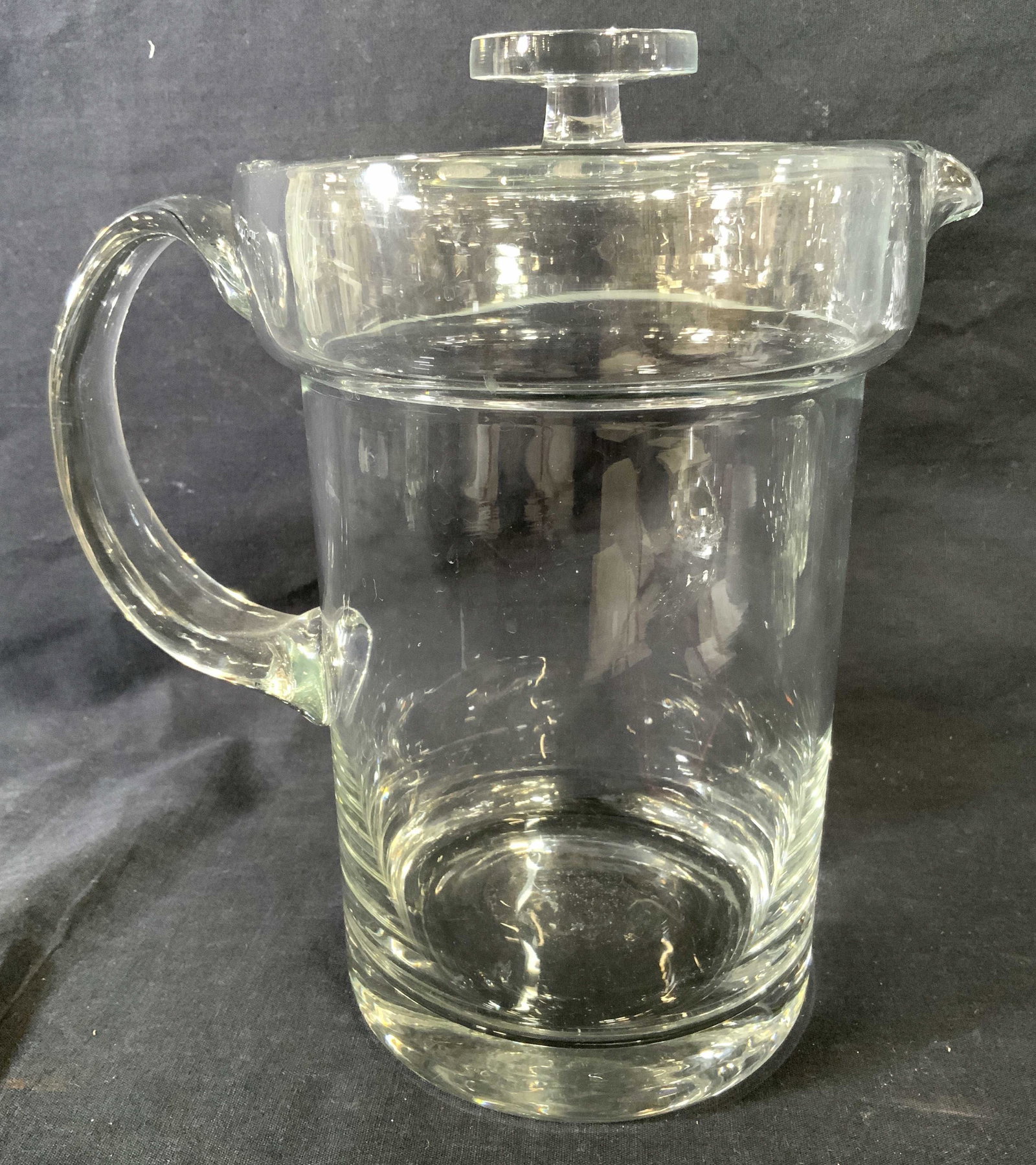 Glass Beverage Pitcher With Lid: Pitcher is glass. Piece has handle, spout and lid with knob style handle. Piece measures approx 10 inches tall 9 inches deep 6 inches wide. This item was generously donated by Regis Philbin’s family