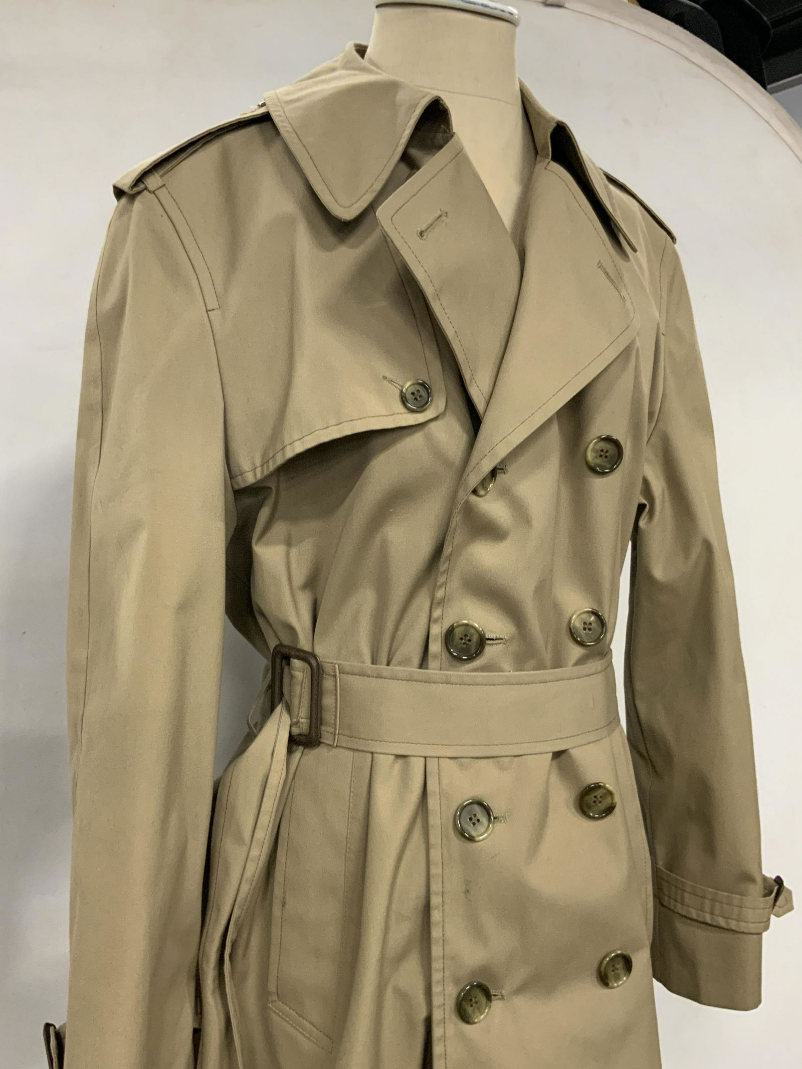 JOY PHILBIN London Fog Belted Jacket: A neutral toned London Fog jacket once owned by Joy Philbin. The piece possesses button closures and a fabric belt closure. There are belt accents on the sleeves as well. Two exterior side pockets, Ap
