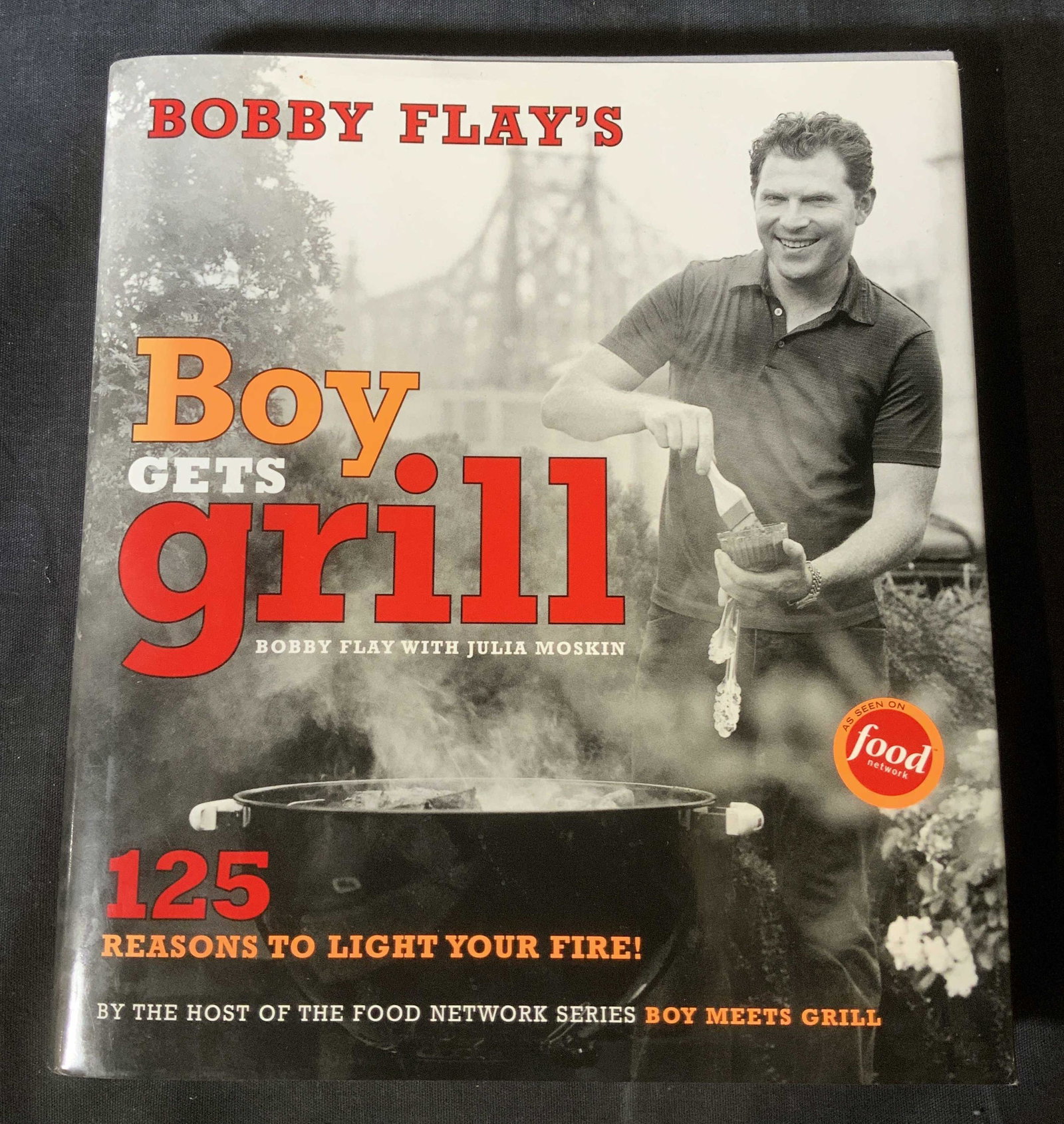 Signed BOBBY FLAY Boy gets Grill Cookbook: Signed BOBBY FLAY Boy gets Grill Cookbook, signature reads ‘Light your fire! Bobby Flay’, inscription reads ‘Bobby Flay’s Boy get Grill Bobby Flay with Julia Moskin’, measures 9 1/2 x 8 3/8 