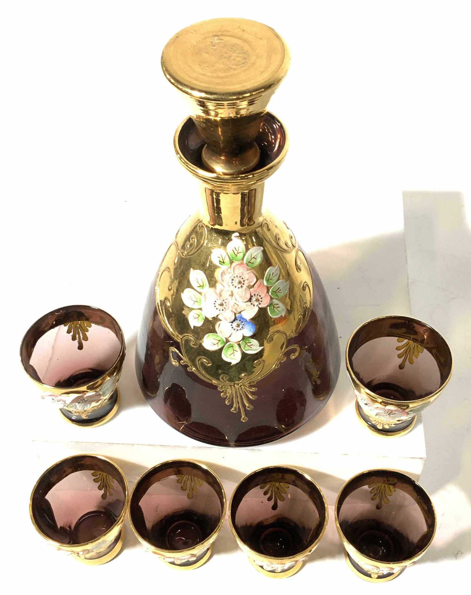 HANDMADE AMETHYST BOHEMIA Decanter Set 7,: Czechoslovakia. Hand painted paste up and sold gilt AMETHYST DECANTER AND SHOT GLASS SET BOHEMIA Ware. Possibly vintage, set includes hand formed decanter with all gilt stopper, 8 in. Ht, 4.5 in wide.
