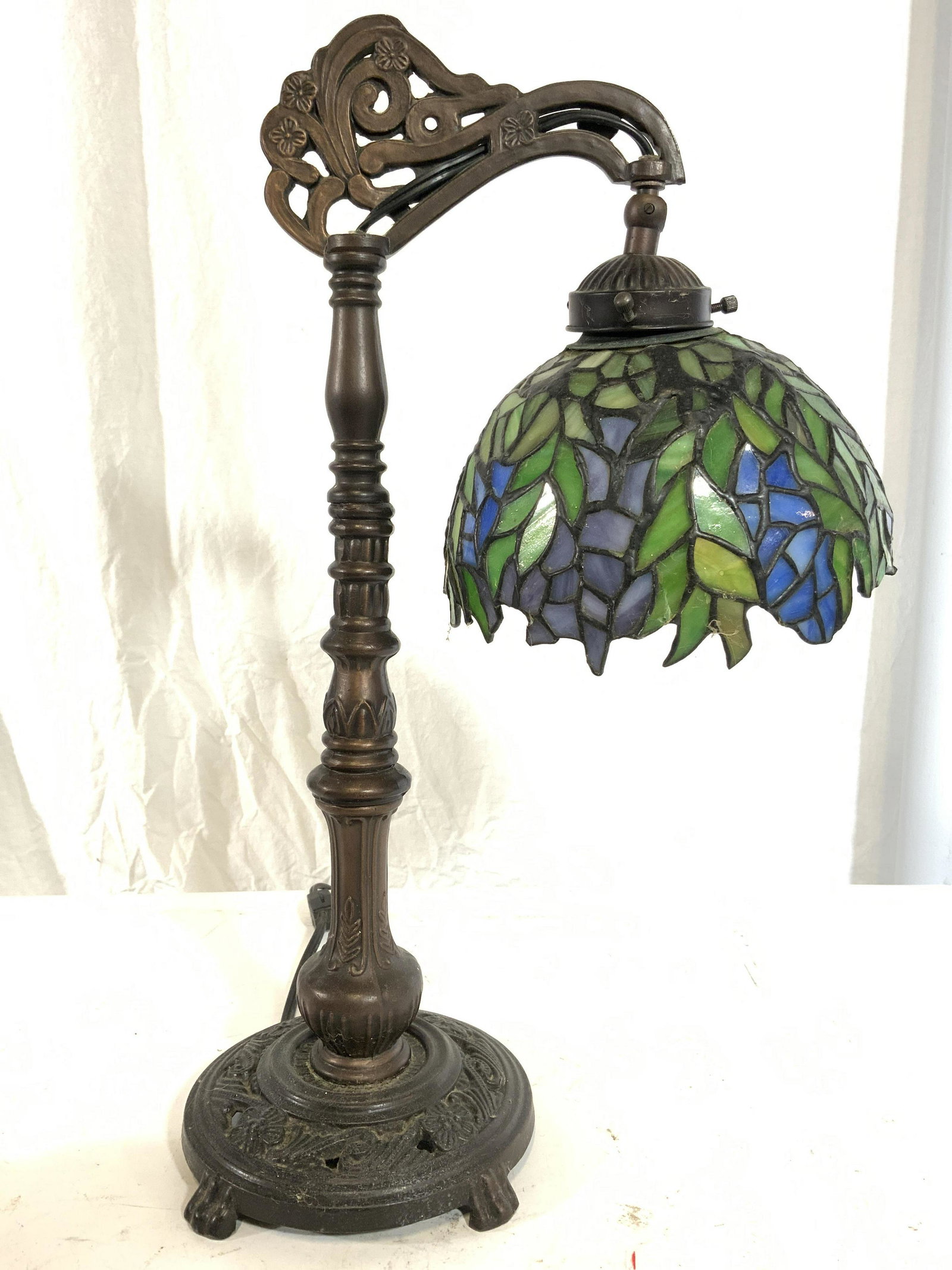 DALE TIFFANY Stained Glass Shade Footed Lamp: Underside has tag which reads DALE TIFFANY. Shade appears to be stained glass, slag glass. Piece has intricately detailed metal base. Base is footed. Shade has blue & green toned detail. Arm appears t