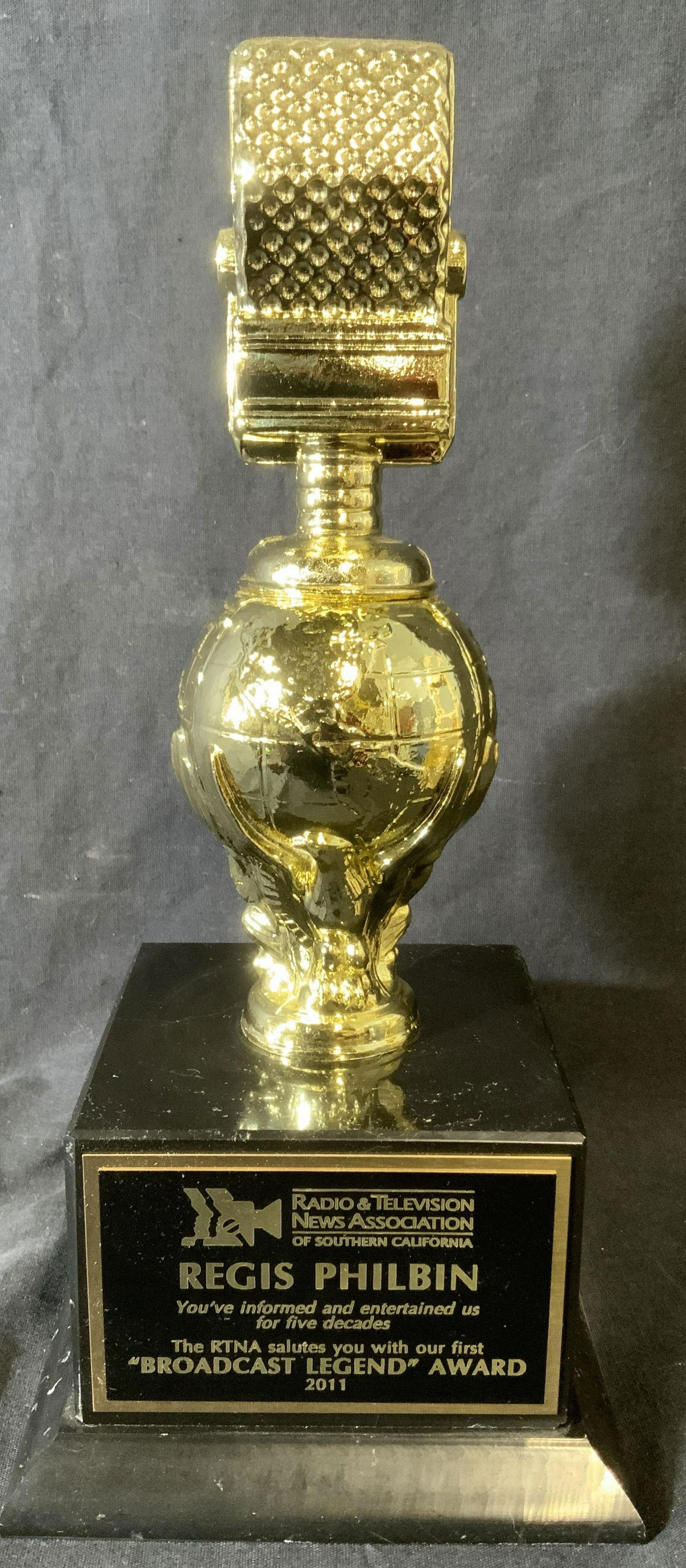 REGIS PHILBIN RADIO&TELEVISION NEWS ASSOC. TROPHY: RADIO & TELEVISION NEWS ASSOCIATION trophy, originally presented to REGIS PHILBIN. Trophy is crafted from gilded metal, base appears to be slate. Plaque reads as RADIO & TELEVISION NEWS ASSOCIATION OF