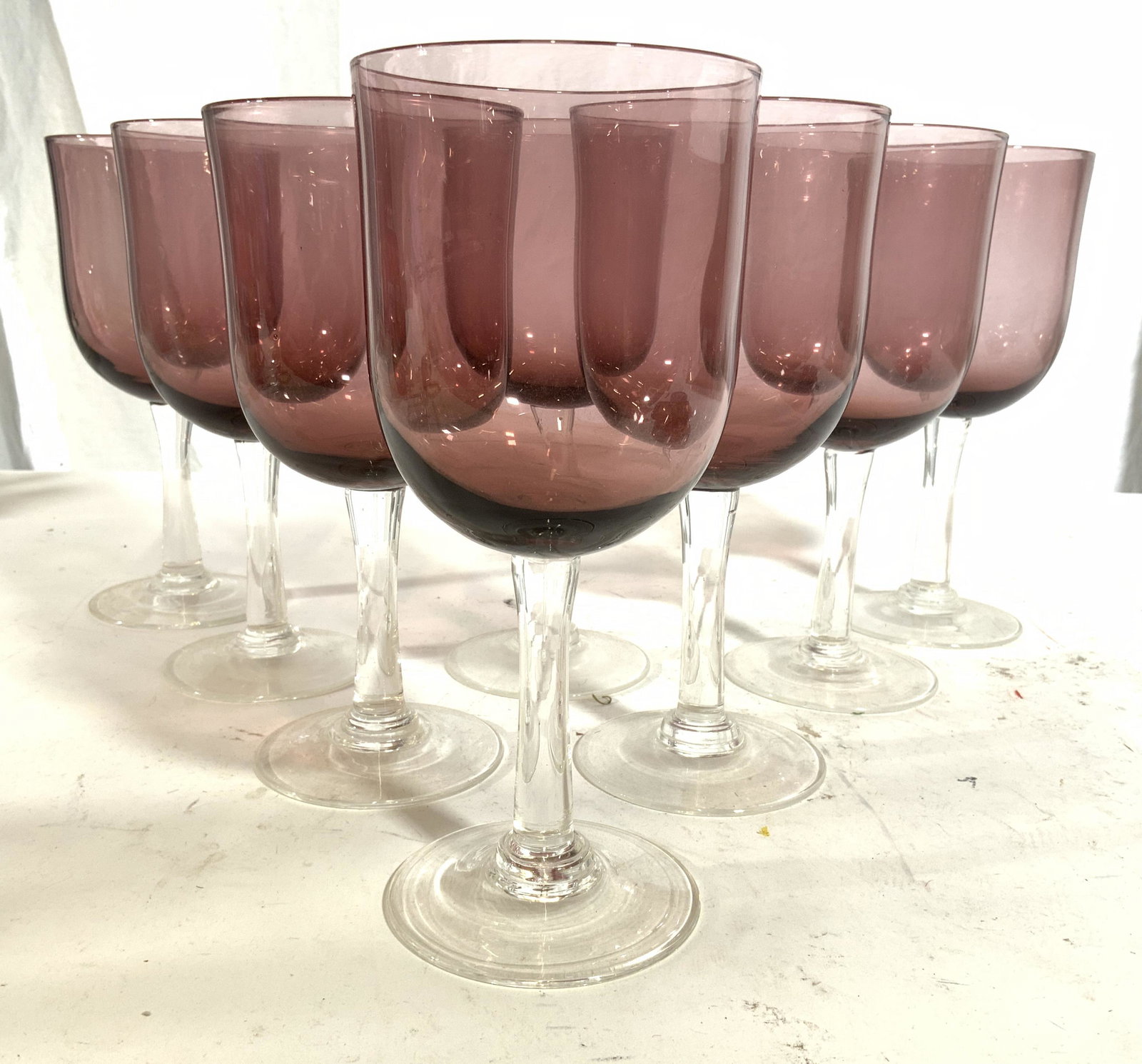 Set 8 Purple Glass Stemware: Lot includes 8 glasses. Each glass is purple toned. Each measures approx 7.75 inches tall 3.5 inches wide. Stemware, glassware, Barware, wine glasses, beverage glasses. This item was generously donate