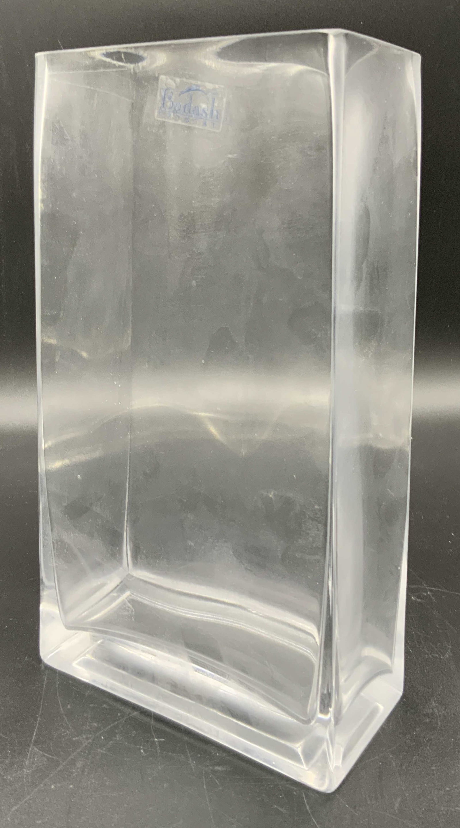 BADASH Signed Crystal Rectangular Form Vase: A colorless square form crystal vase. Has a sticker reading BADASH CRYSTAL. Some surface wear. Approx. 9.5H x 4.5W in. This item was generously donated by Regis Philbin’s family and was the property