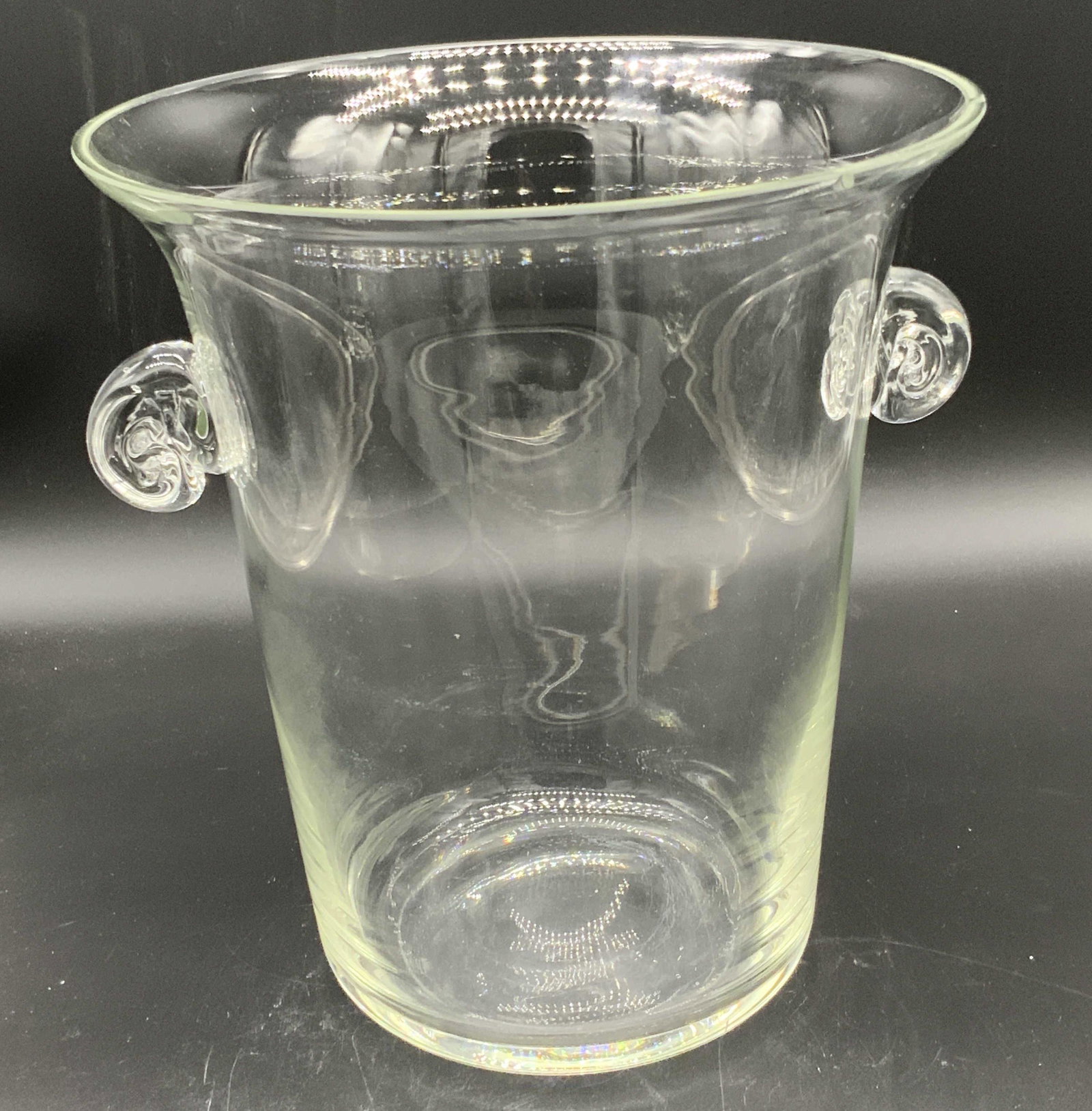 Crystal Ice Bucket W/ Twin Handles: A colorless crystal ice bucket / bowl. The piece has twin handles on either side. Piece is Weighty. Some surface wear, chips along rim. Approx. 10H x 8.5W in. This item was generously donated by Regis