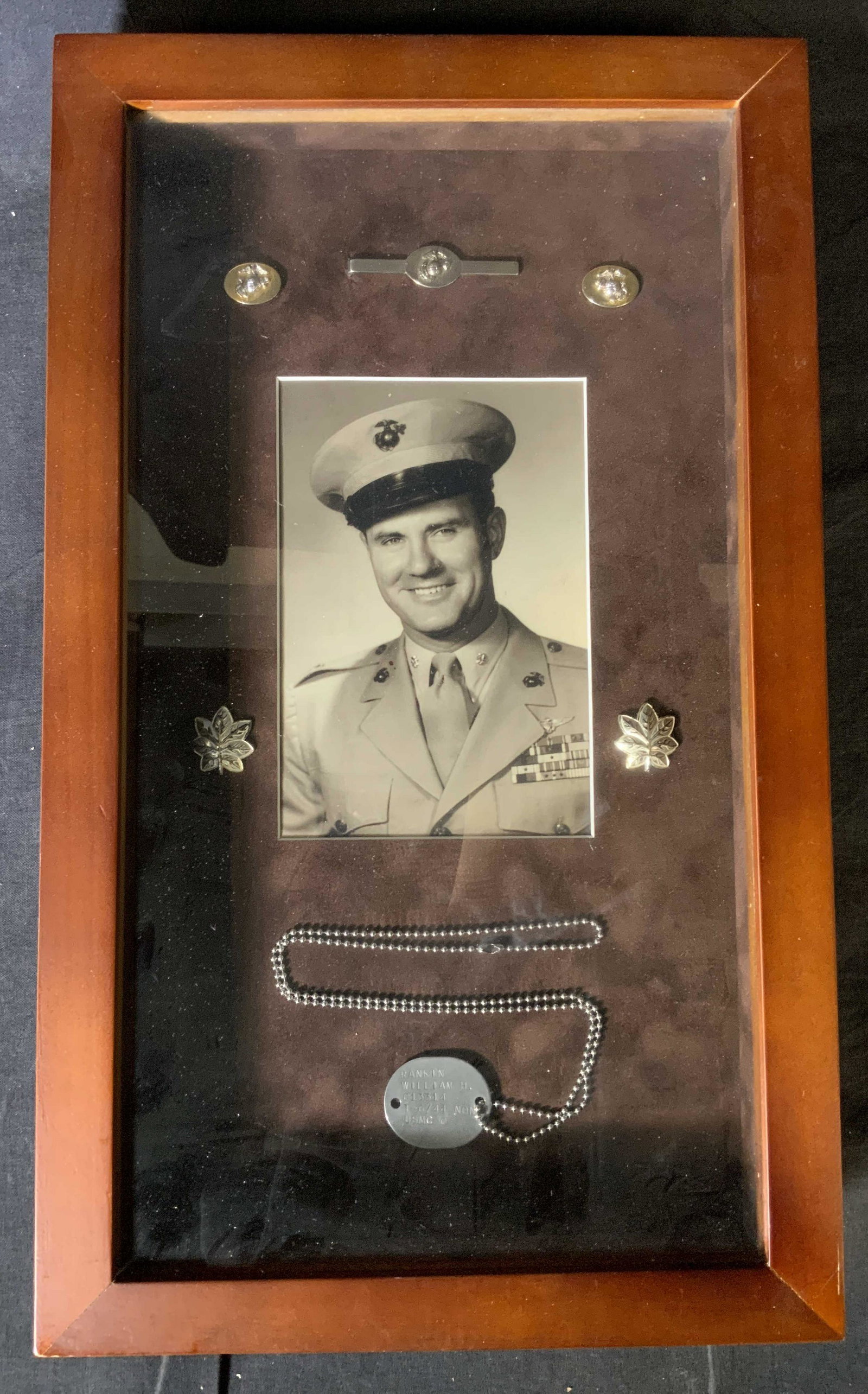 WILLIAM H RANKIN Military Memorabilia: WILLIAM H RANKIN Military Memorabilia, inscription to dog tag reads ‘Rankin William H 013314 T-6/44 NONE USMC O’, measures 17 1/8 x 10 1/4 inches, wooden shadow box, some surface wear to wood, Thi