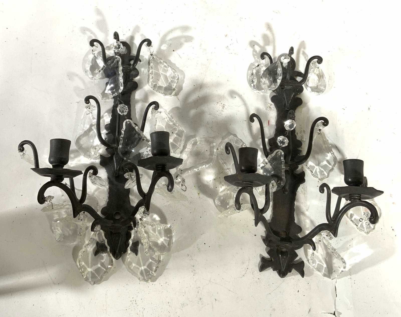 Pair Metal Wall Sconces W Prisms: Lot includes 2 wall sconces. Each are black toned & metal. Both pieces include multiple hanging prisms. Sconces has 2 arms each. Sconces measure approx 13 inches tall 10 inches wide. Sconces, wall sco