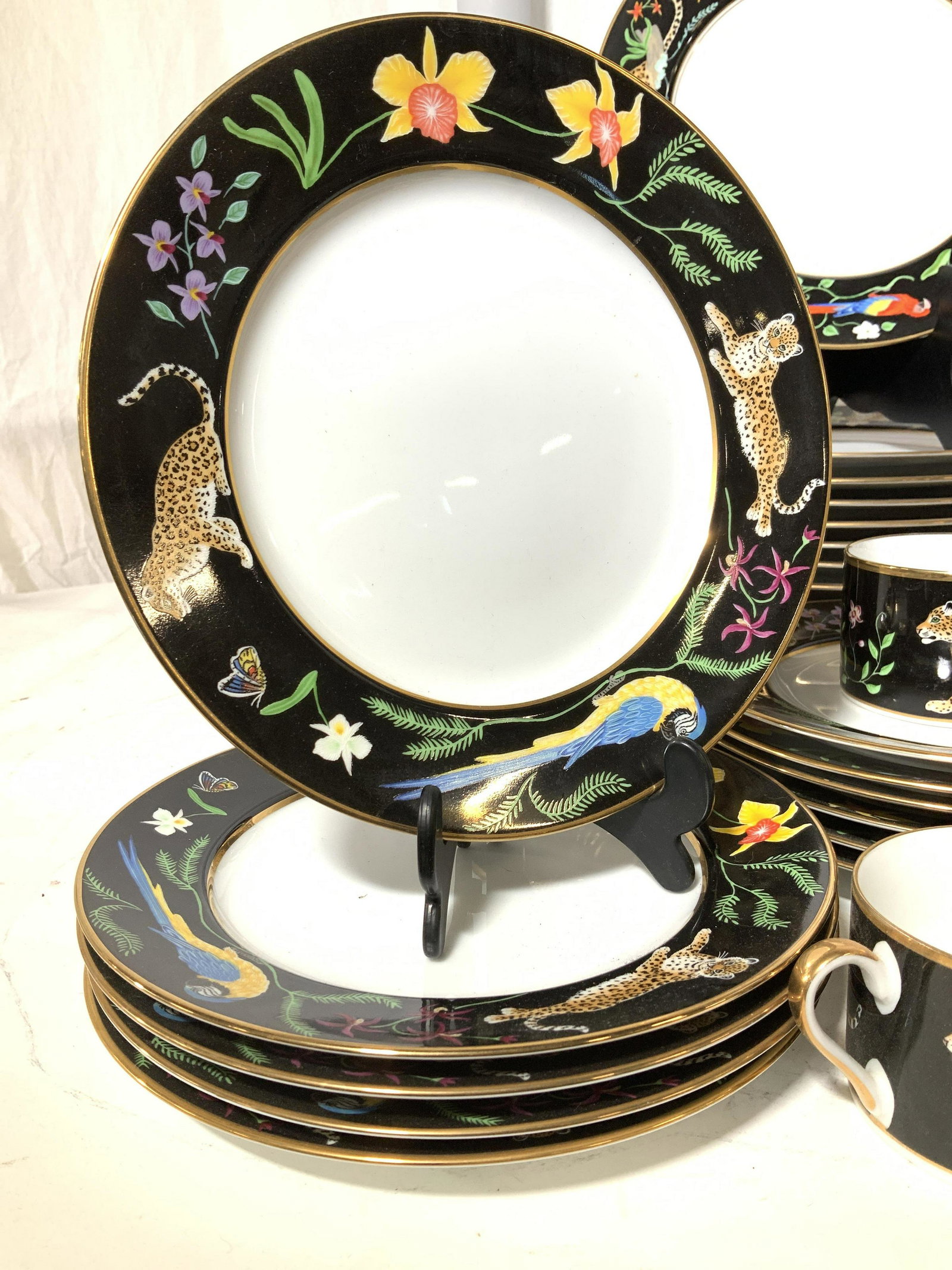 24 K Gd Lynn Chase Jaguar Jungle Chinaware Set39: Luxury Porcelain China Plate set depicting Orchids, Jaguars, scarlet macaw in jungle atmosphere , all pieces Hallmarked , c. 1988 Lynn chase designs and decorated with 24k yellow gold rims. 12 dinner 