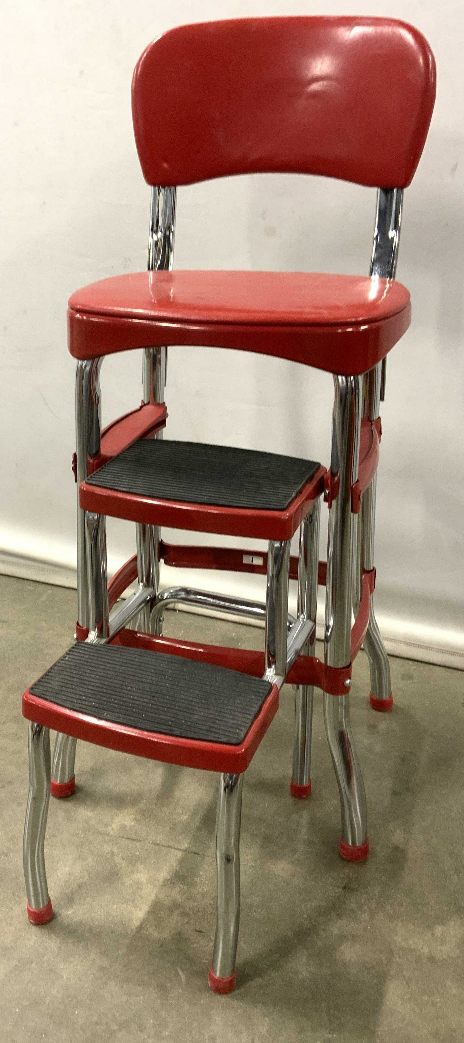 Vintage Red COSCO Stepstool Chair: Underside of piece has tag which reads COSCO. Piece has tones of red black and silver. Frame is metal. Seat and backrest appear to possibly be genuine leather. Piece has attached 2 step step stool. Fe
