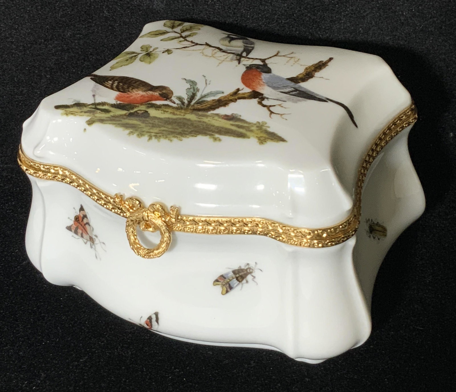 LIMOGES French Porcelain Bird Motif Trinket Box: A white porcelain trinket box decorated with painted depictions of birds and birds out in a nature setting. Irregular square form. The piece operates with hinge hardware. Hardware is gold toned metal.
