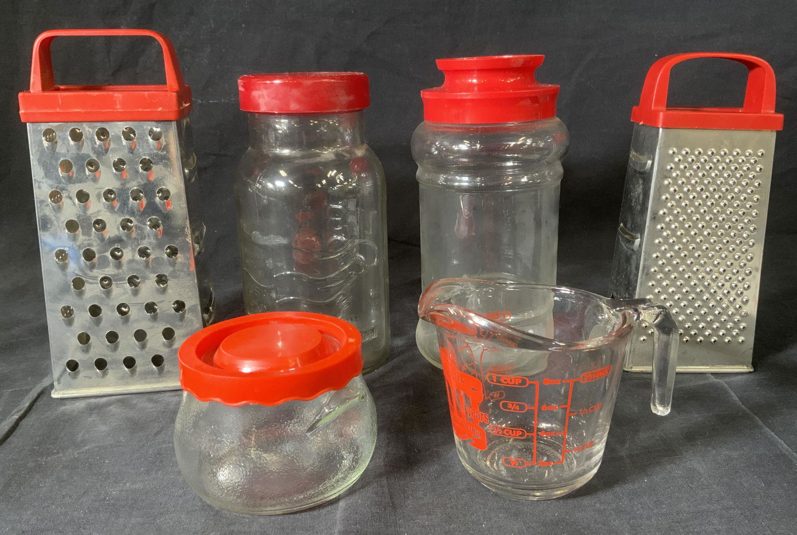 Lot 6 Graters, Jars, & Measuring Cup: Lot 6 Graters, Jars, & Measuring Cup, inscriptions read ‘9254 S’, ‘Maxwell House USA Sponsor 1992 US Olympic Team’, and ‘Badcock 100 Years’, smallest jar measures 2 7/8 inches tall x 4 inc