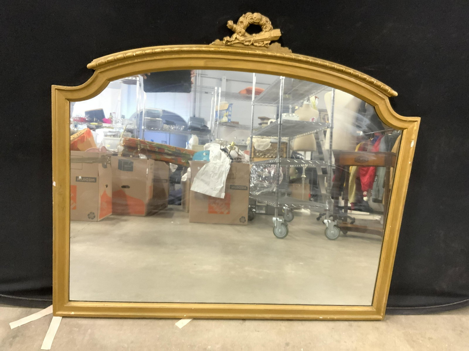 Vintage Ornate Gold Leaf Frame Mirror: Mirror is vintage possibly antique. Piece has ornate detail depicting floral structures at top. Upper area of mirror frame has slight arch. Piece measures approx 38 inches tall 42 inches long. Mirror,