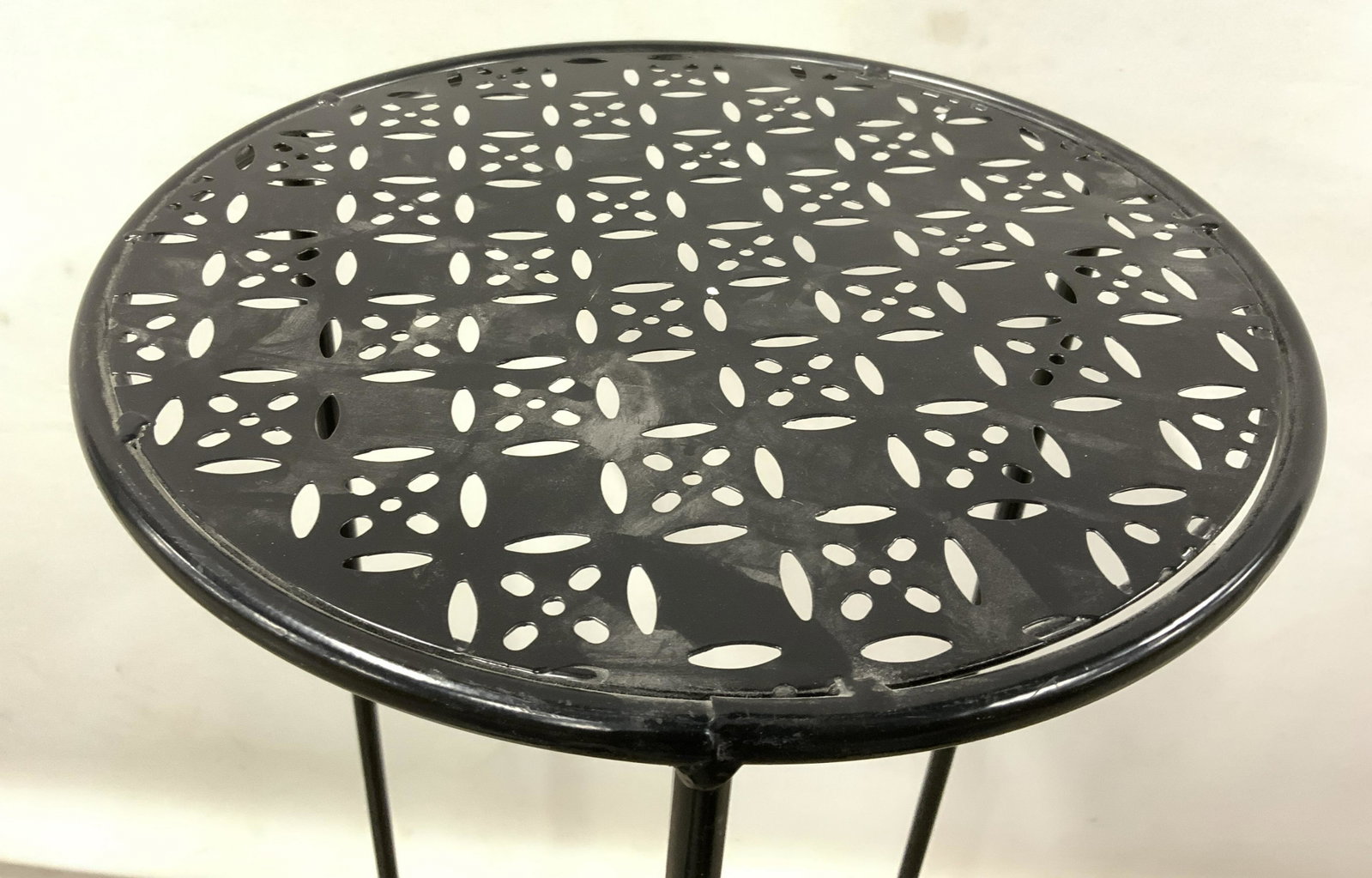 Circular Metal Plant Stand Pedestal Side Table: Plant stand is black toned and metal. Piece has geometric pierced detail. Table has 3 legs with circular shaped stretcher in between. Legs are footed. Piece measures approx 26 inches tall 12 inches di