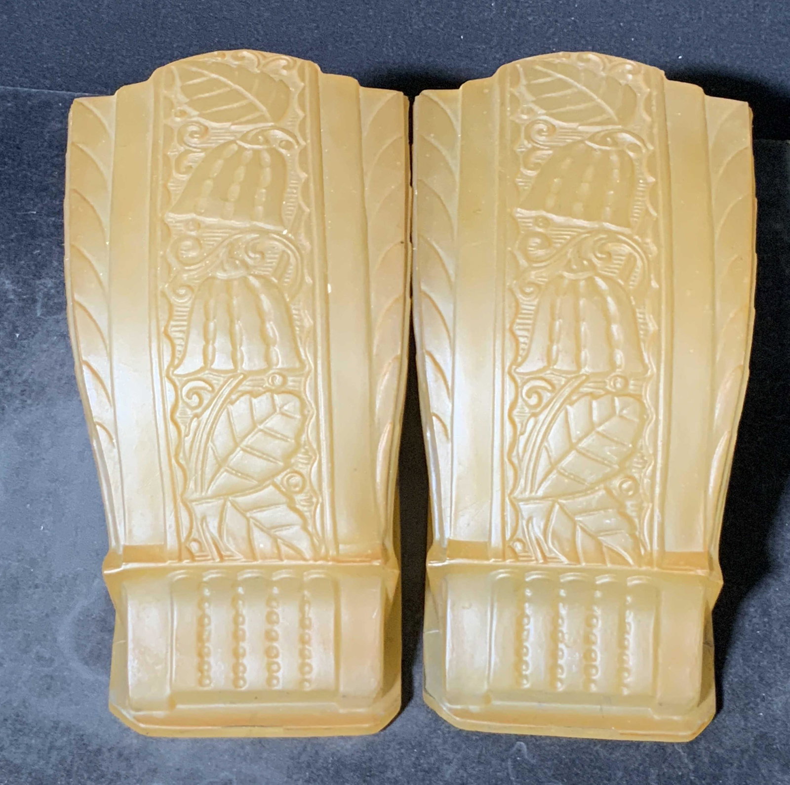 Pair Vintage Orange Art Glass Wall Sconce Covers: Thick walled glass wall sconce covers. Embossed and etched glass designs depict floral motifs. Pieces are a muted orange hue. Pieces possess some chipping. Approx. 7L x 4W in. Property of Multigenerat