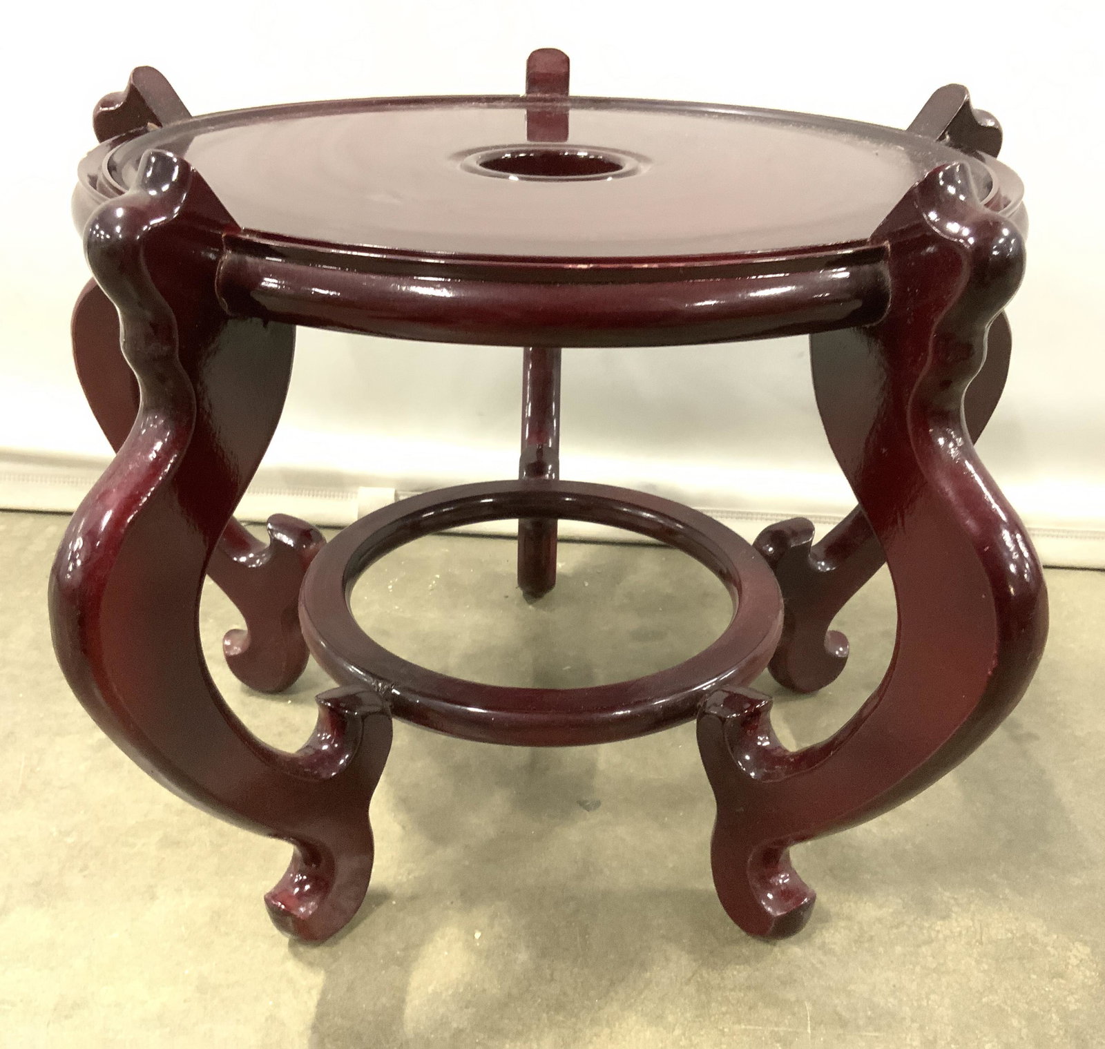 Vintage Carved Wooden Asian Pedestal: Pedestal is wooden, porcelain mahogany. Piece is vintage possibly antique. Stand has 5 feet with circular stretcher in between. Center has circular shaped negative space. Piece measures approx 18 inch