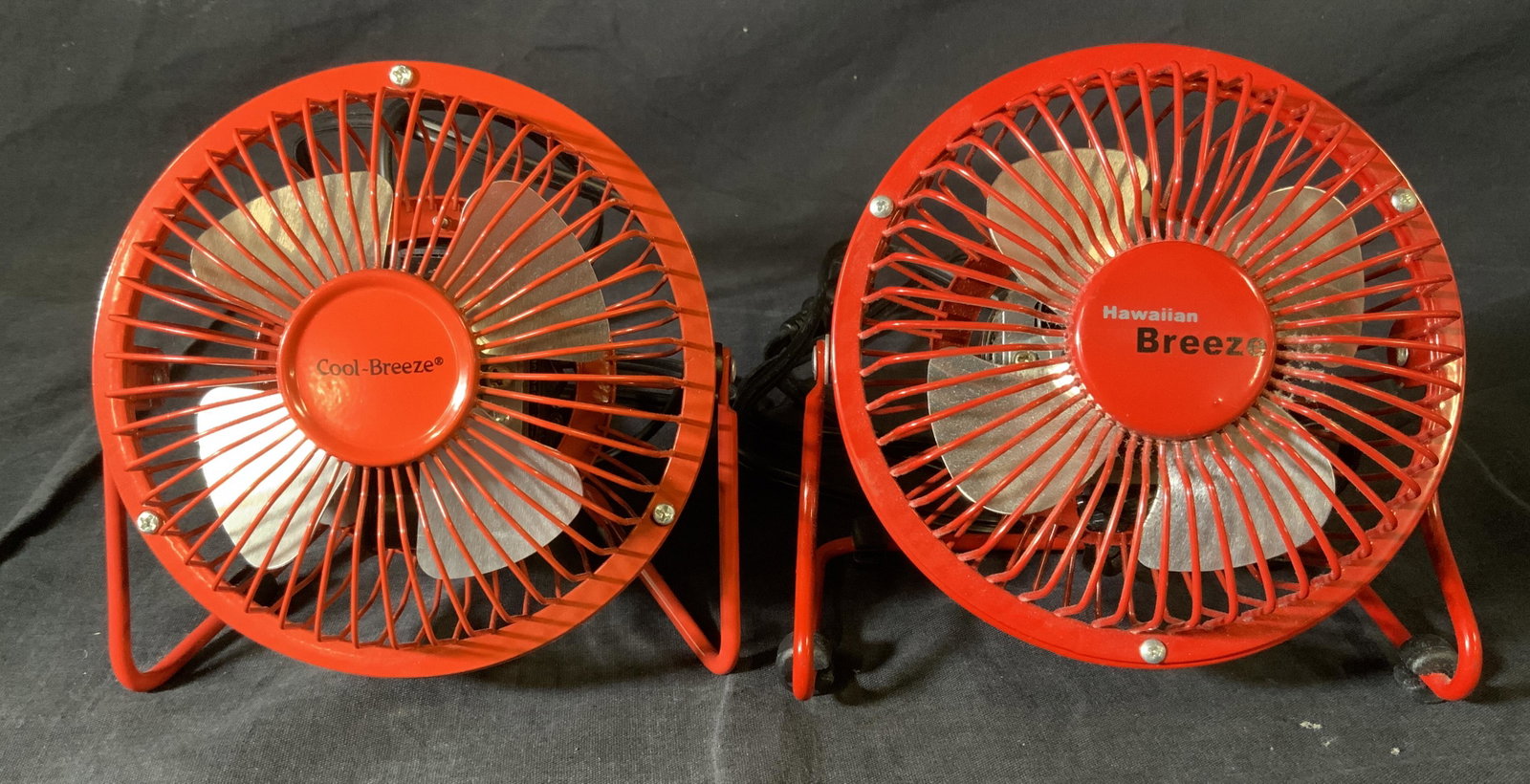 Lot 2 Red Electric Fans: Lot 2 Red Electric Fans, inscriptions read ‘Cool Breeze’ and ‘Hawaiian Breeze’, both measure approximately 5 7/8 inches tall x 6 inches at widest point, some surface wear to pieces, not tested