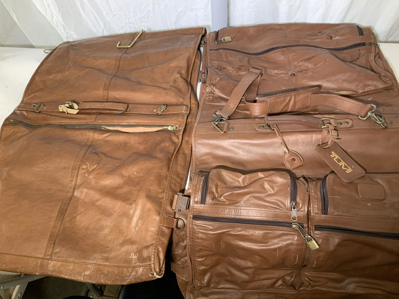 Pair TUMI Brown Leather Garment Bags, Vintage: All leather garment bags, weighted, both Labeled TUMI, pre owned and used. Locks and keys for one bag on exterior zipper compartments with no interior or exterior zipper compartment issues. Carry hand
