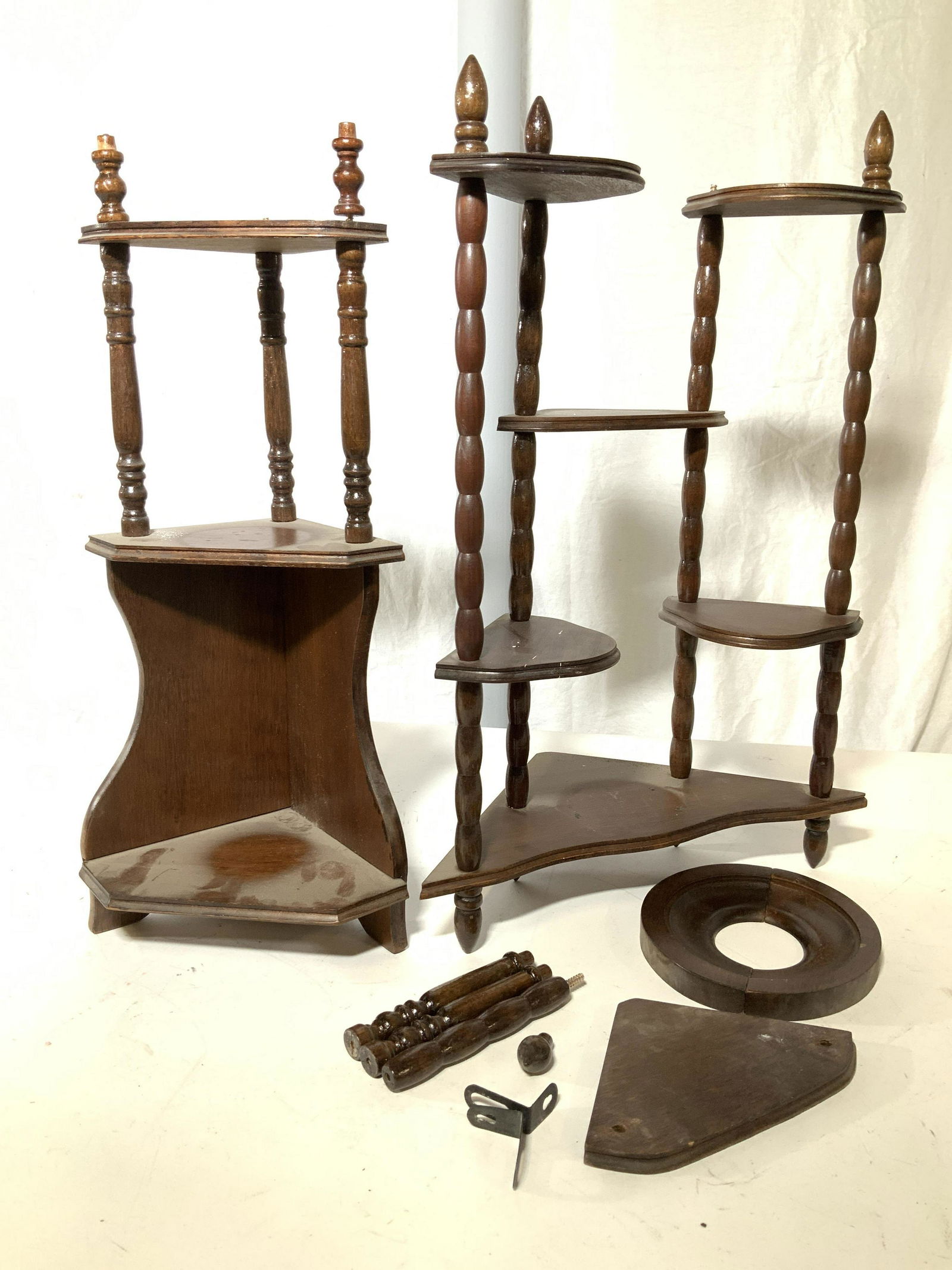 Vntg lot 2 Corner Wood Table Display Shelves: Two corner display knick knack shelves, one shelf with multi shelf layers, needs one top finial, 20 in ht, 13.5 in. Width on diagonal. other corner shelf has two shelf layers, needs a top finial or ca
