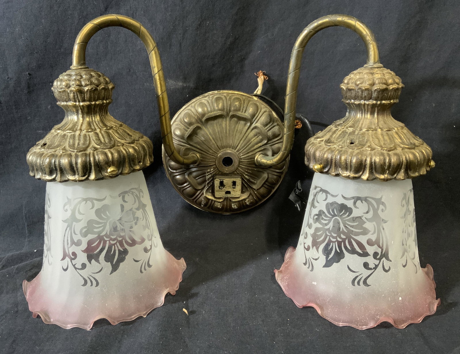Vintage Two Armed Brass Wall Sconce: Vintage brass wall sconce. Decorated with cast detailing, arms resemble flowers. Lamp shades are glass, and frosted, edges are colored pink, floral patterns are etched into the shades. Measures approx