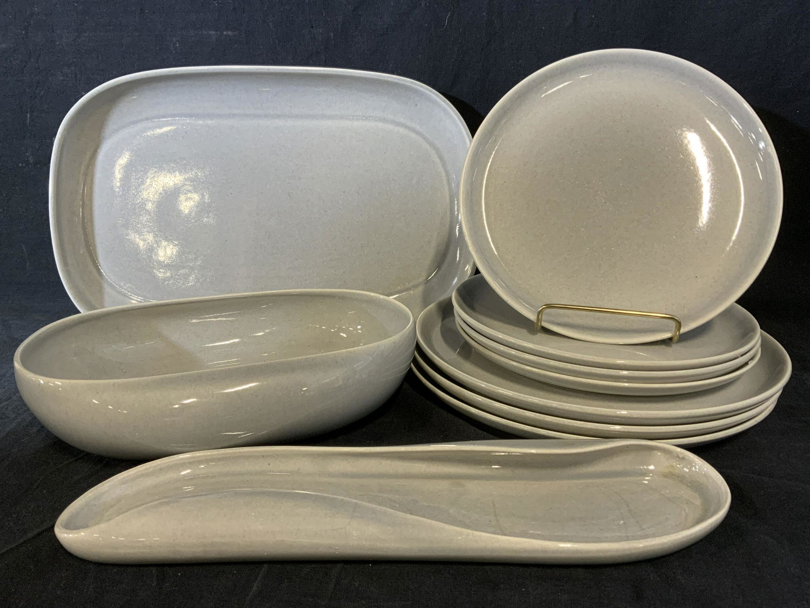 Lot 10 RUSSEL WRIGHT Ceramic Serving Ware: Lot of 10 ceramic dishes. Includes 7 plates, 2 trays, and 1 bowl. Underside reads as RUSSEL WRIGHT MFG BY STEUBENVILLE. Largest piece measures approx 13.5 inches Long, 9 inches W. Wear is consistent w