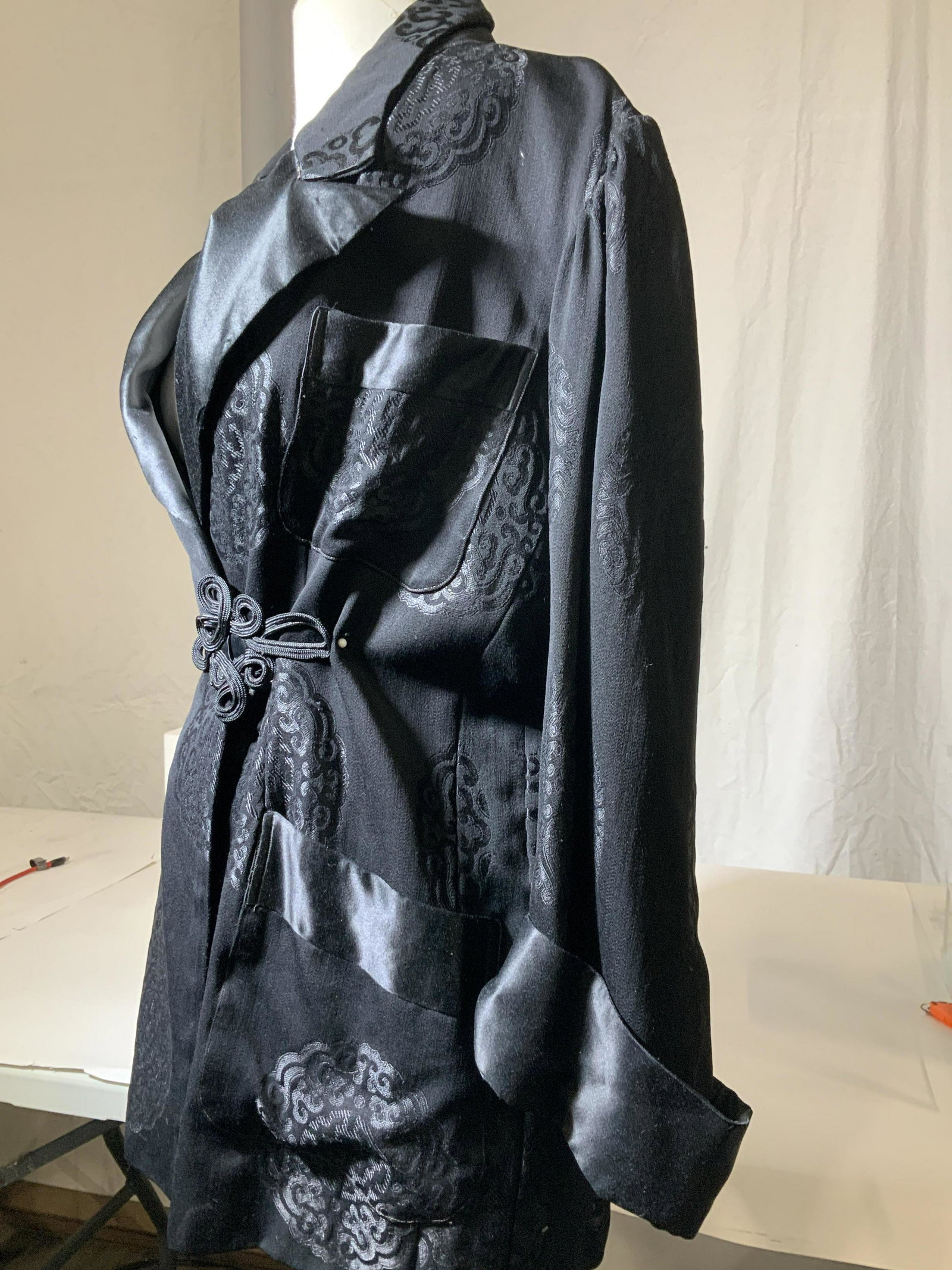 Black Asian Shou Symbol Dress Jacket: Vintage Asian dress/ evening jacket with shou symbol pattern, soft hand fabric, large hand pockets, tuxedo shawl collar, pleated shoulder hem, shiny sateen - like fabric. 28 in long, 35 in waist. Need