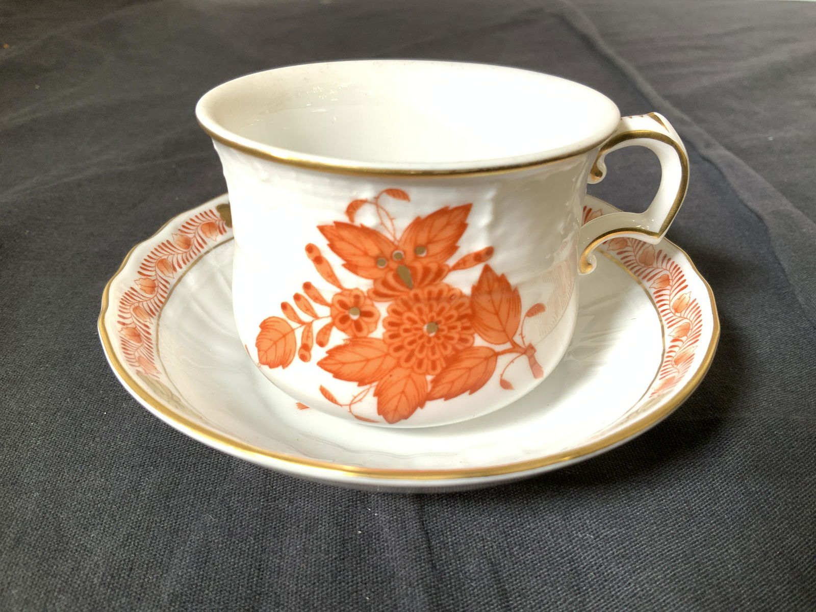 HEREND HUNGARY Porcelain Tea Cup & Saucer: Vintage, c. 1930 Apponyi Flowers Herend Pattern , created in honor of Count Albert Apponyi and influence by Asia. Gilt rimmed tea cup and saucer with rustic orange hand painted florals. Cup 2 in tall,