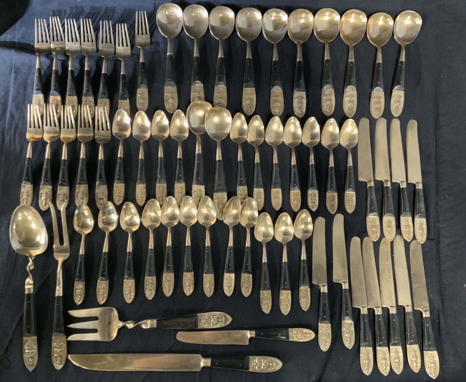 SIAM Group Lot Silverware: 12 forks, 35 spoons,12 butter knives,1 carving fork, 1 carving knife, and salad servers. All pieces are finished with a gold wash, handles all read as SIAM, a Buddha-like figure is cast into each hand