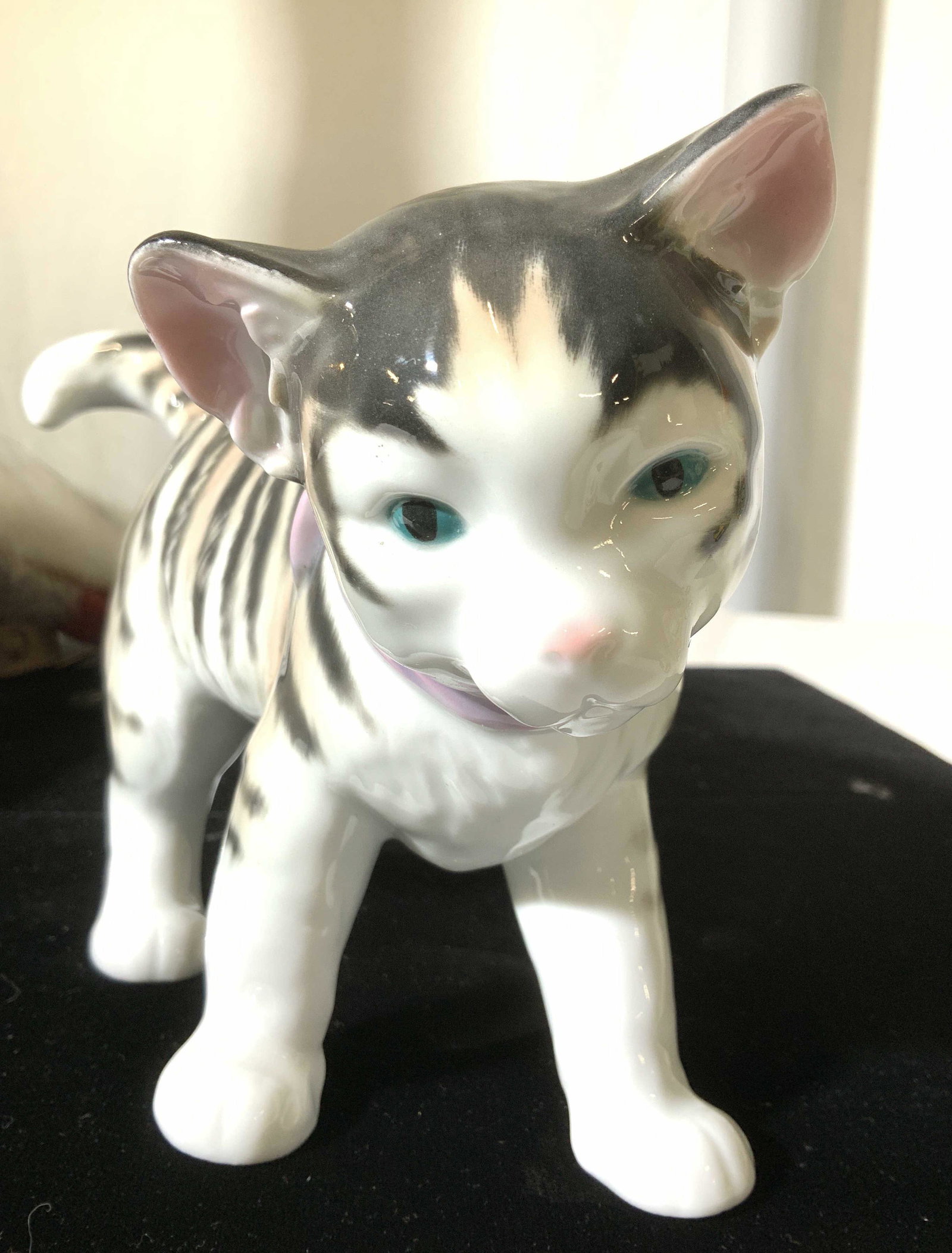 ENS Porzellan Volkstedt Cat w Bow: Karl Ens Germany Tabby Cat Statue with green eyes and a purple bow. Hallmarked ‘ ENS Porzellan Volkstedt’ in green ink under Vase, 5.5 in ht, 11 in long, 3.5 in wide. German Porcelain cat statue, 