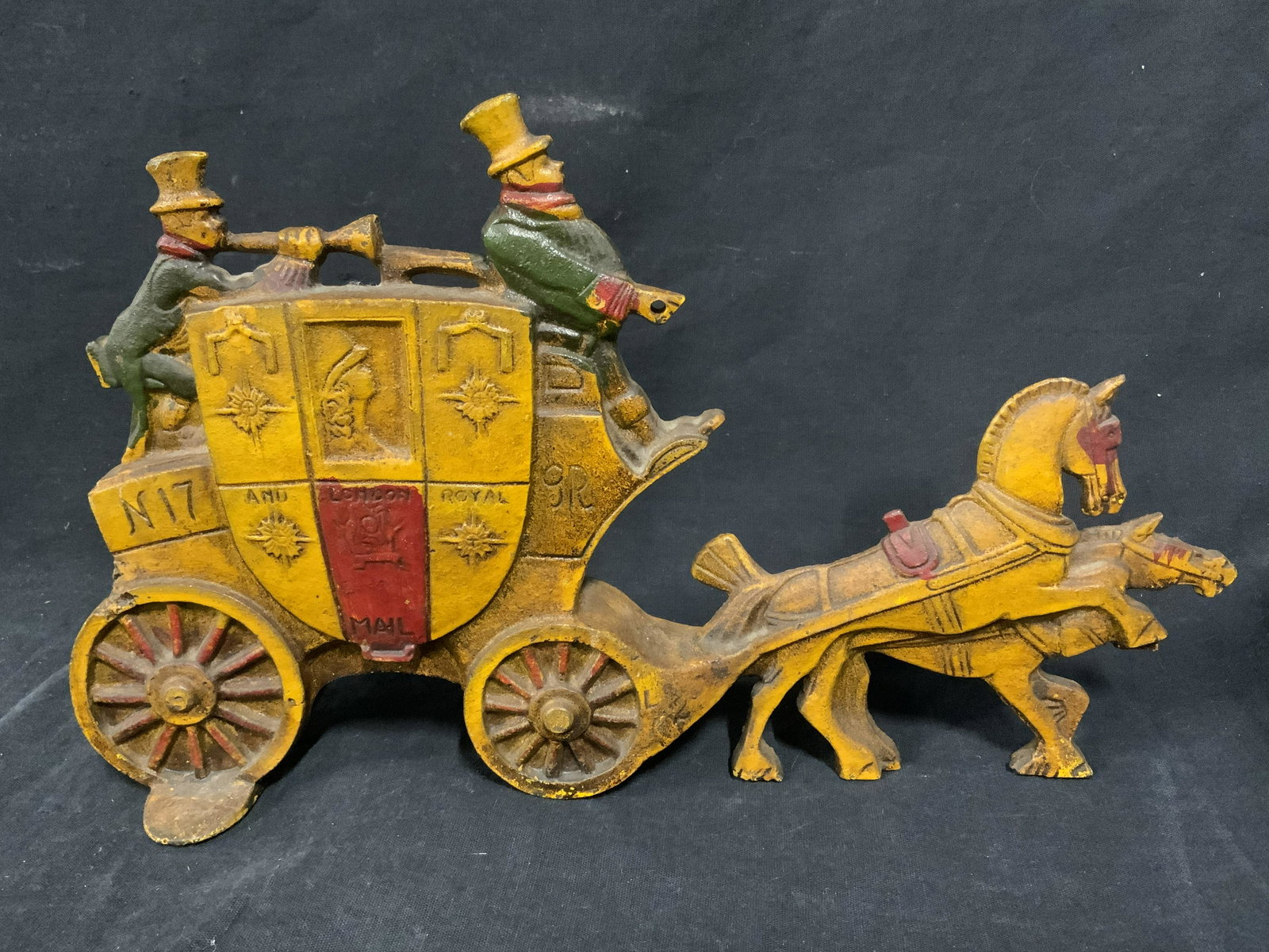 Cast Iron Horse Drawn Carriage Doorstop: Cast iron door stop, possibly vintage, possibly antique. Resembles a horse drawn carriage, colored in yellow, red, and green tones. Reads as LONDON ROYAL MAIL. Measures approx 7.25 inches H, and 12.25