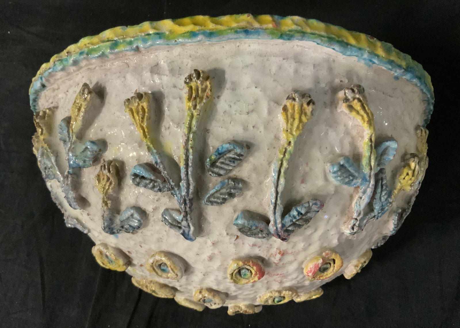 Folk Art Earthenware Planter: Hand mad, hand painted, earthenware planter. Decorated with several flowers and flower petals done in relief. Metal wire is affixed, allows for mounting and hanging. Measures approx 6.5 inches H, and 