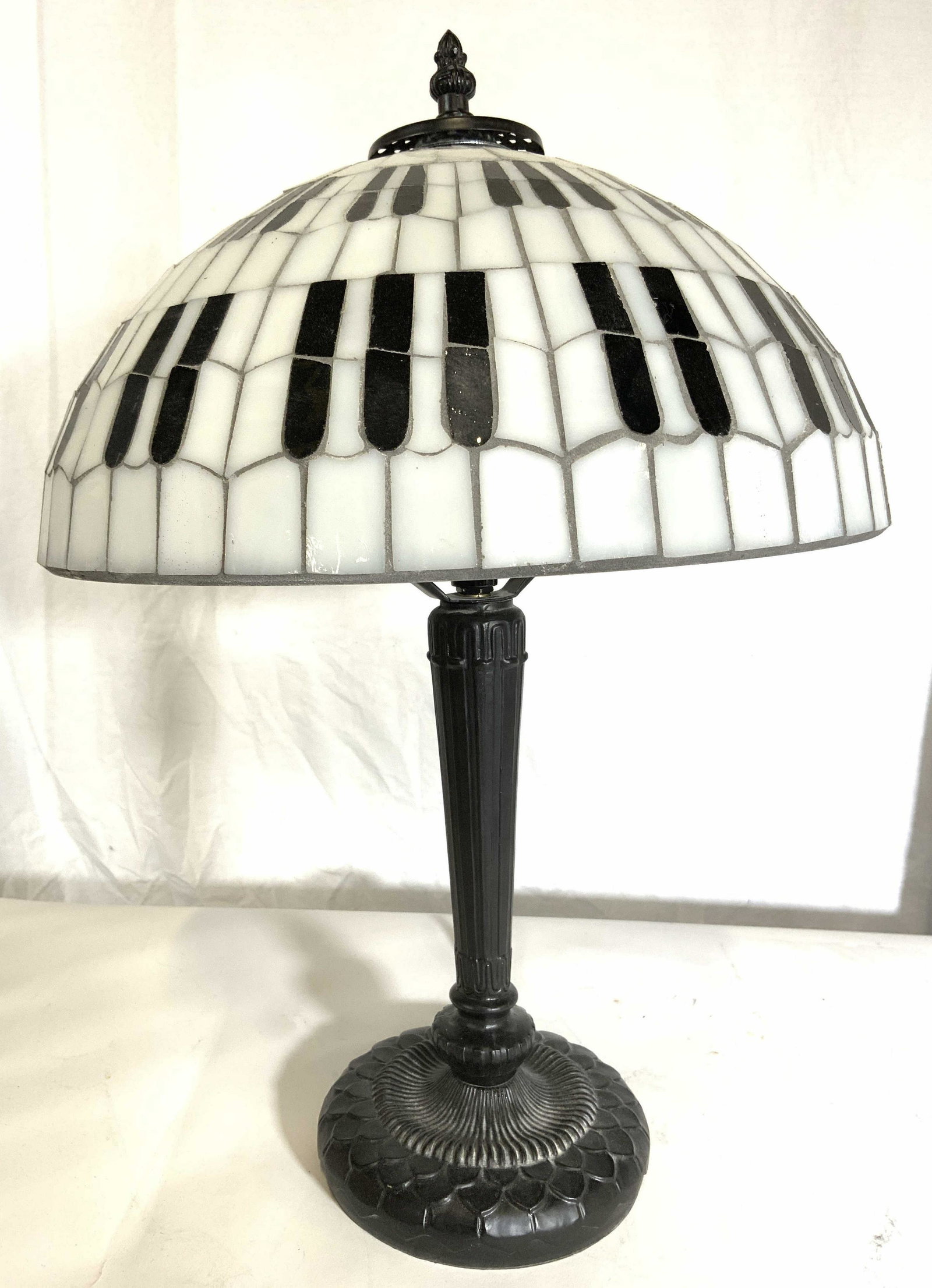 ALBERT ELOVITZ Stained Glass Shade Lamp: Under Has tag which reads ALBERT ELOVITZ. Lamp has stained glass, slag glass shade. Piece is Tiffany Style. Shade has black & white toned detail resembling piano keys. Piece measures approx 18 inches 