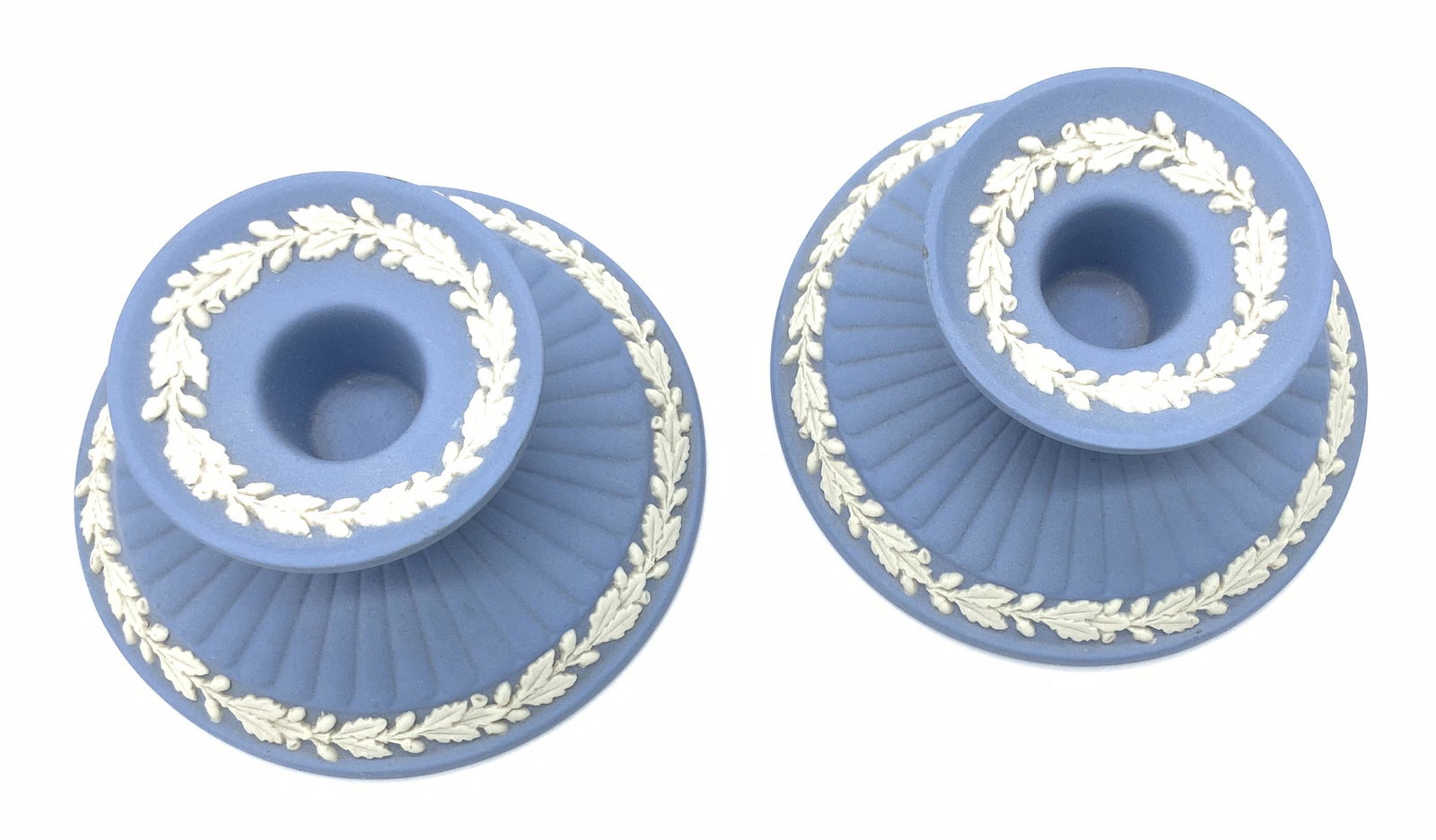 Pair Wedgwood Porcelain Laurel Candlesticks: Blue Wedgwood Porcelain Candlesticks with neoclassical Laurel pattern in relief , 4 in. Wide, 2 in ht. Hallmarked Impressed with Wedgwood- Made in England and M and U, or U, 75, & HD. Wedgwood Candles