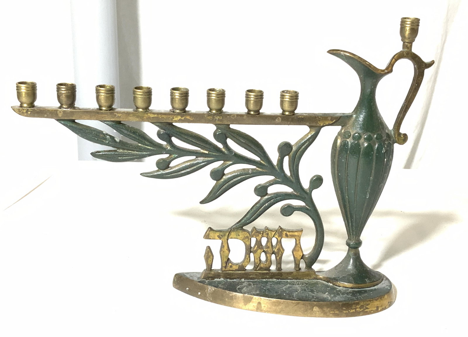Collectible Enameled Claret Jug Menorah, Israel: Decorative menorah, green enamel over brass, Hallmarked made in Israel. 9 thin candle holders, one on top of a claret pitcher. 10 in long x 7.5 in ht. Brass and Enamel menorah, claret Pitcher menorah,