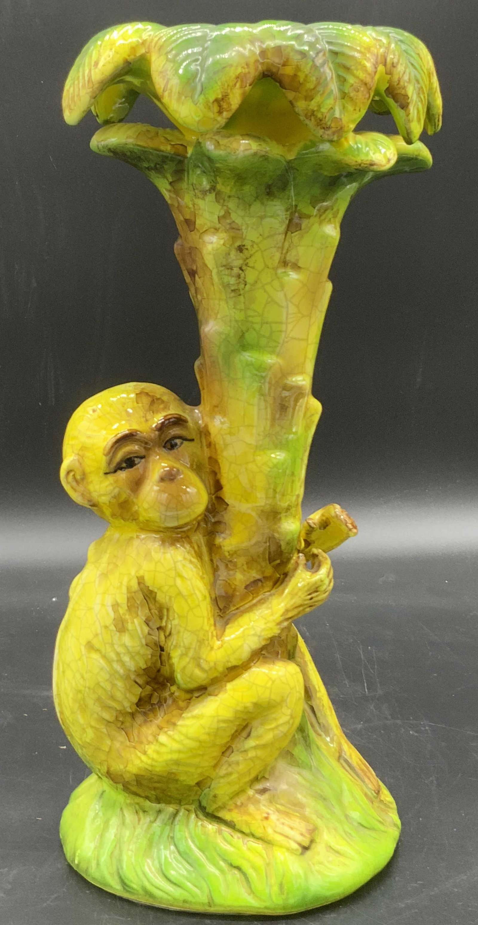 Tabletop Hand Painted Ceramic Monkey Statue: A vibrant yellow and green glazed ceramic monkey statue. The monkey is depicted with their arms wrapped around the trunk of a tree. Embossed details throughout the design. The very top of the tree is