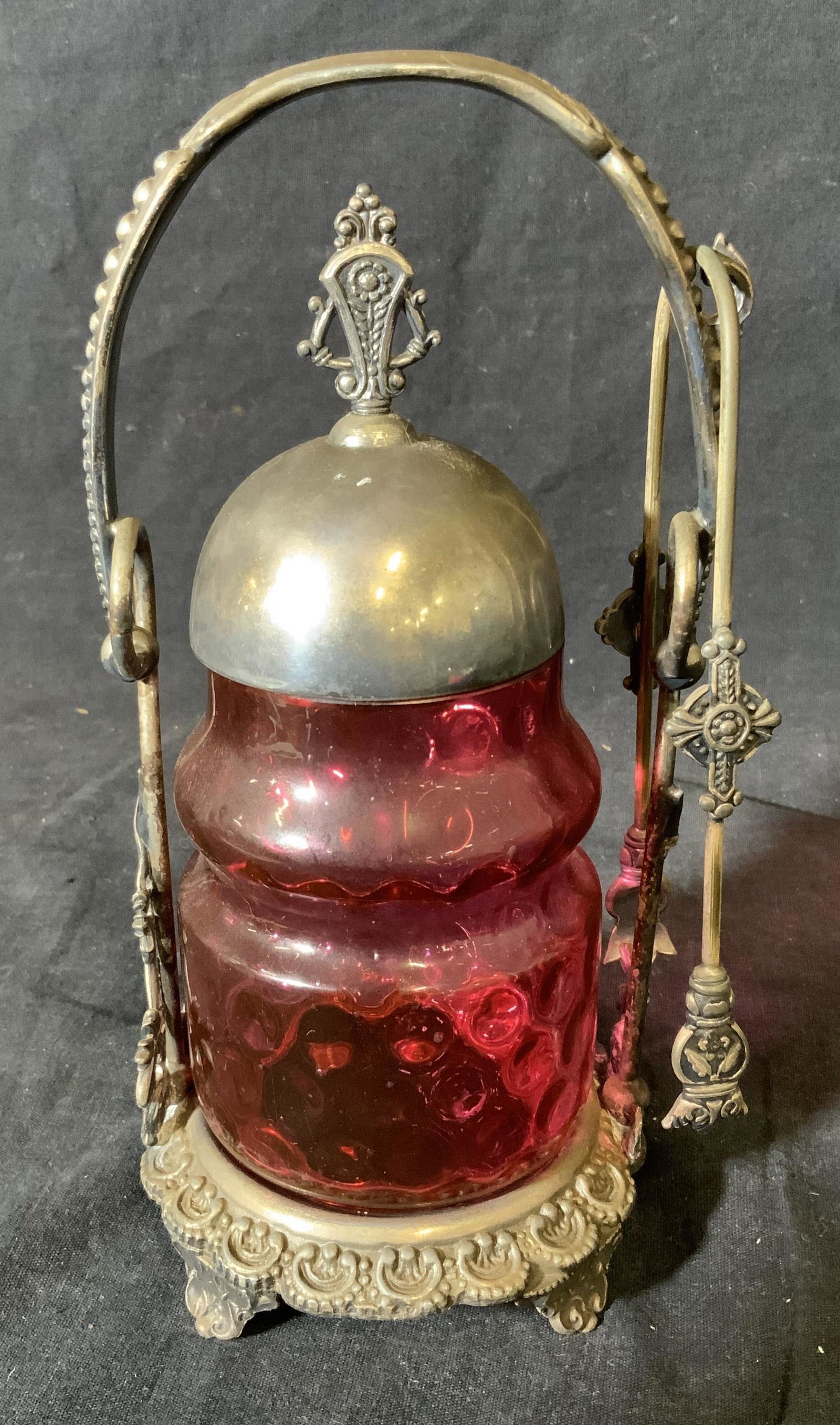 Antique Silver Plated & Glass Pickle Jar: Antique silver plated and glass pickle jar with tongs, body made of a Cranberry colored Art glass with circular designs, lid base/handle and tongs are silver plated, label to interior of lid reads Â�