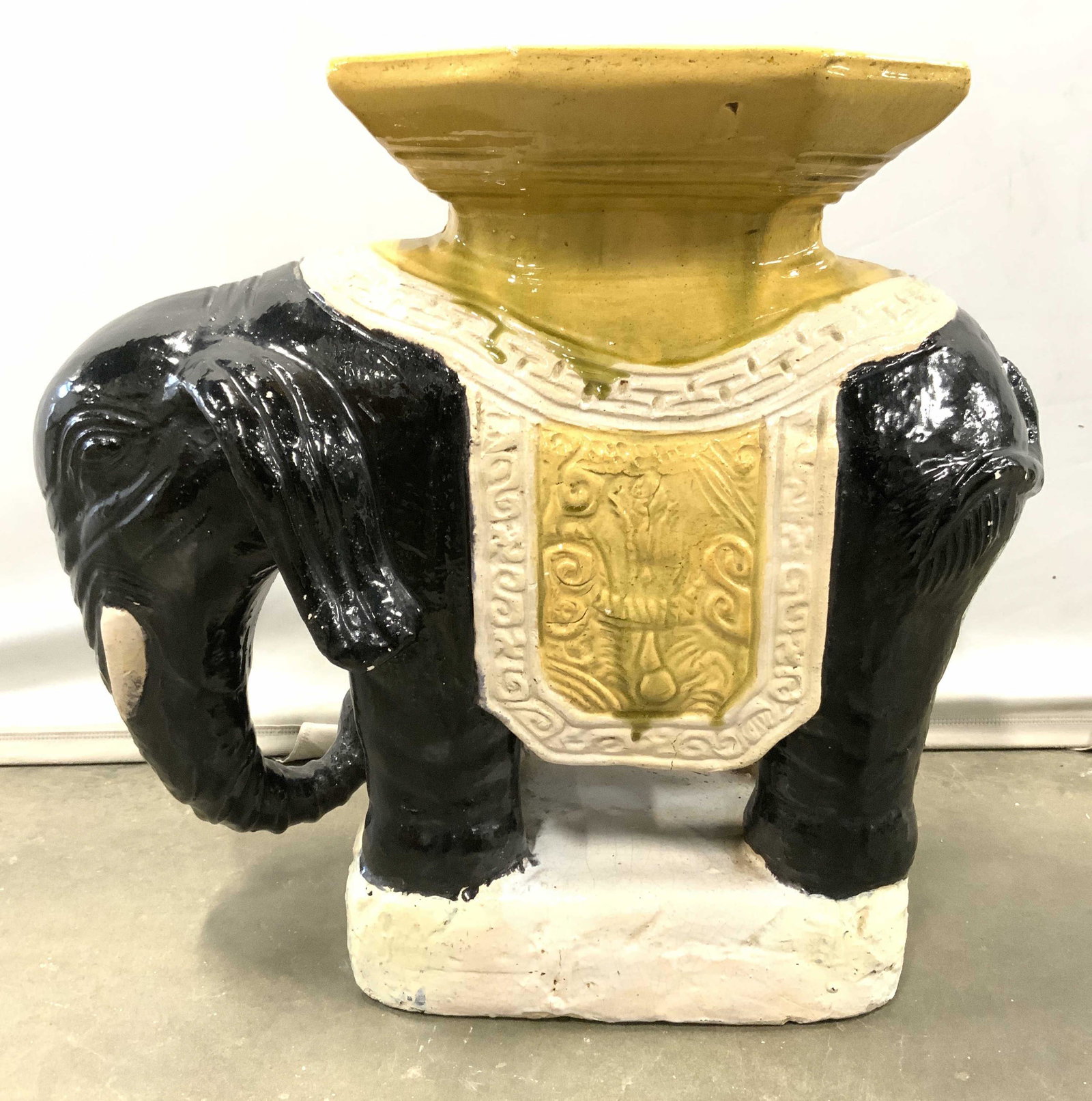Hand Painted Ceramic Elephant Garden Stool: Garden stool appears to be ceramic possibly porcelain. Piece is hand painted with tones of cream, black & gold sides have ornate relief detail. Piece is possibly hand crafted. Garden stool measures ap