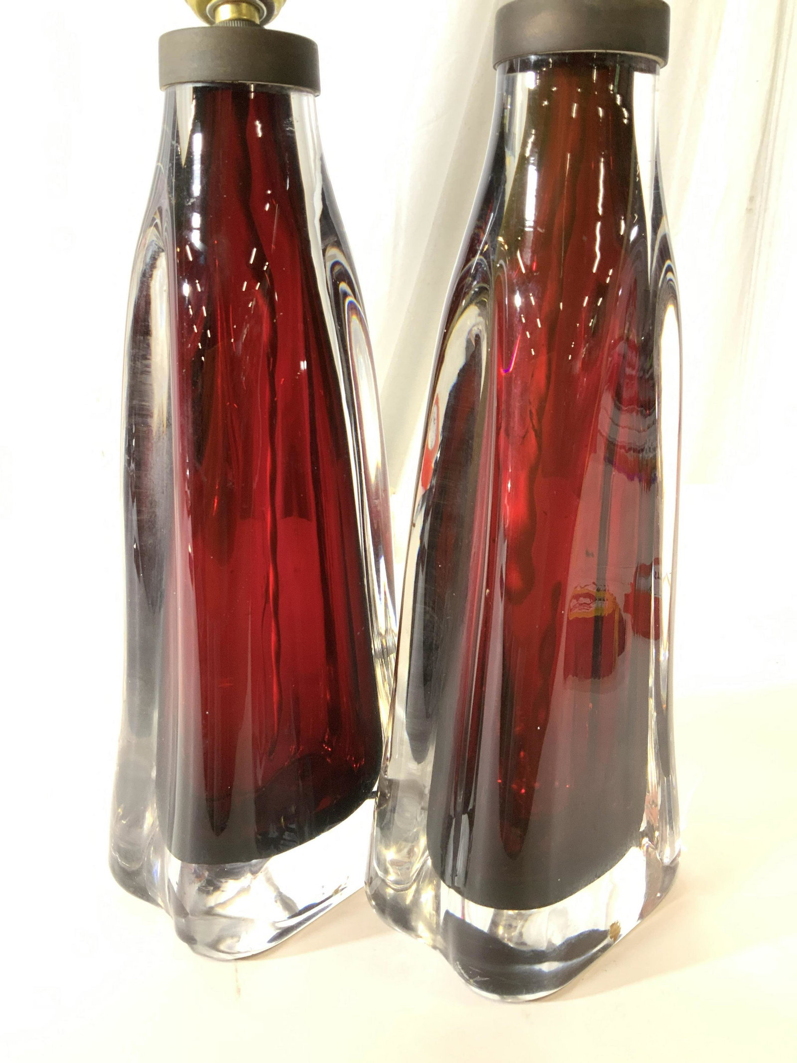 Pair Red Orrefors Crystal Lamps: Triangular shaped lamps with soft rounded edges, interior deep shade of cranberry sour rounded by chunky clear crystal , produced by Orrefors, Sweden, signed and numbered on underside, circa 1960’s,