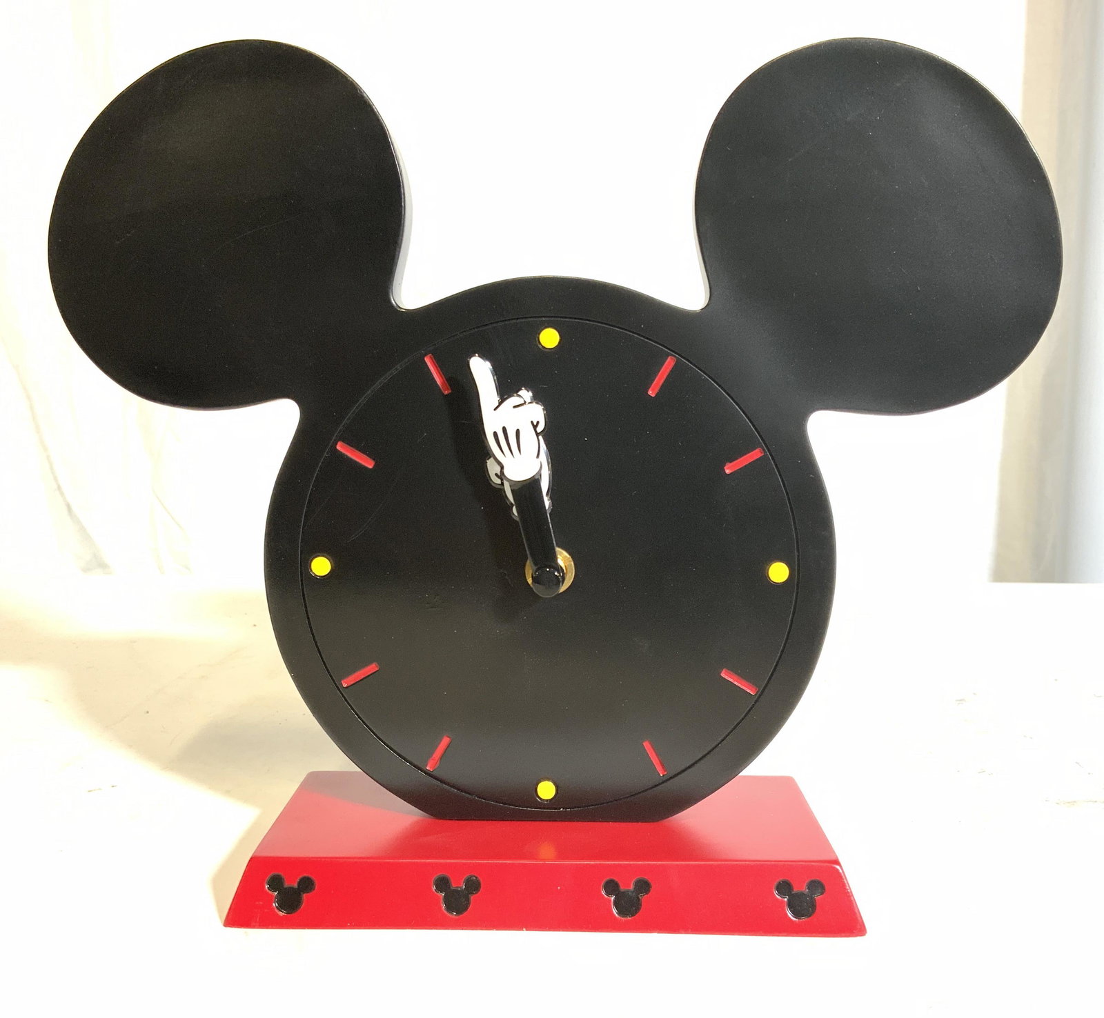 MICKEY ICON CLOCK DISNEY Desk Clock In Box: Box has tag which reads MICKEY ICON CLOCK DISNEY. Clock has Mickey Mouse shape. Includes original box. Piece is black and red toned with white glove hands. Piece measures approx 8 inches tall 9 inches