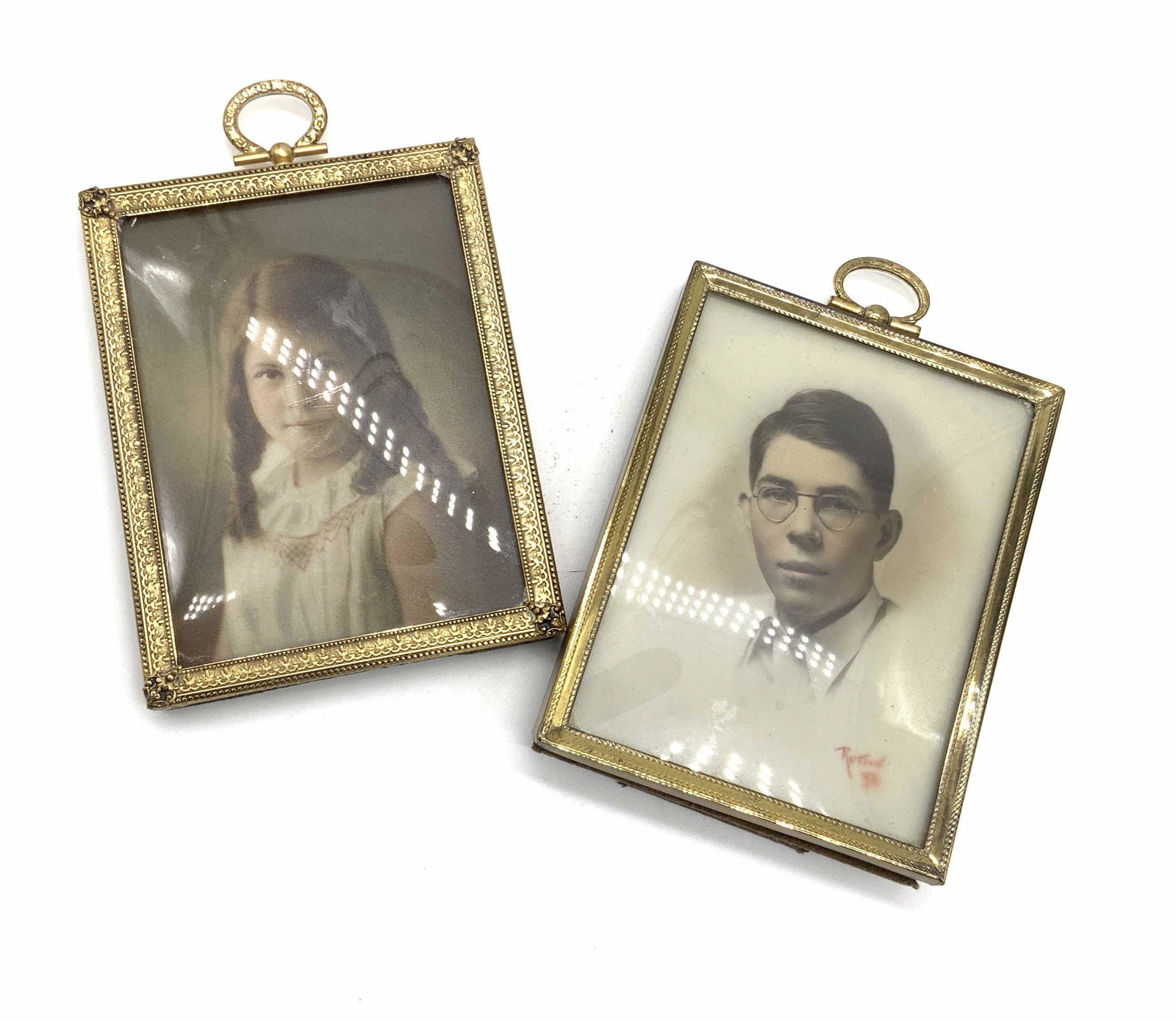 Lot 2 Antique Gold Tone Metal Picture Frames: Two vintage, possibly antique, gold tone metal frames featuring etched metalwork throughout their designs. The tops of the frames have metal hardware for hanging. The reverse of one frame has a kick s