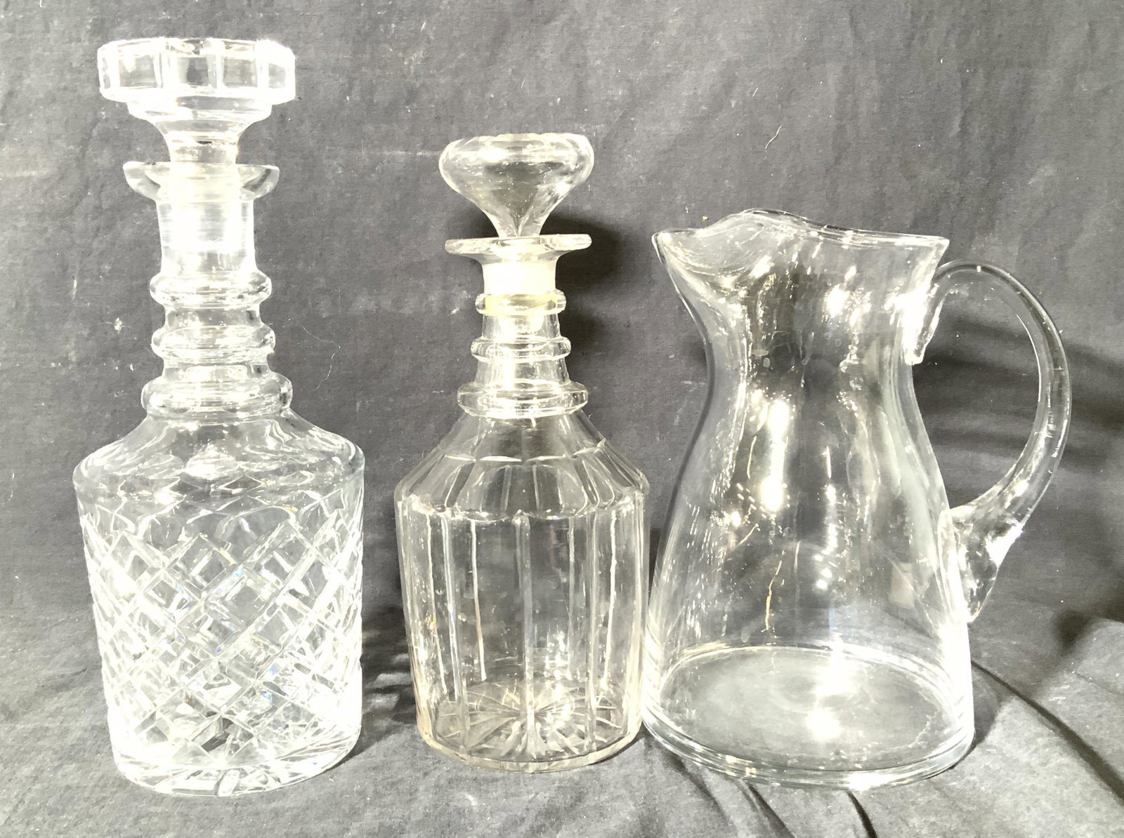 Group 3 Crystal & Glass Barware: Lot 2 decanters with stoppers. One minimalist vintage glass decanter 10 in ht. One cut crystal decanter with Diamond pattern, 11 in ht x 4.5 in width. Glass water/ juice / cocktail pitcher 8.25 in ht 