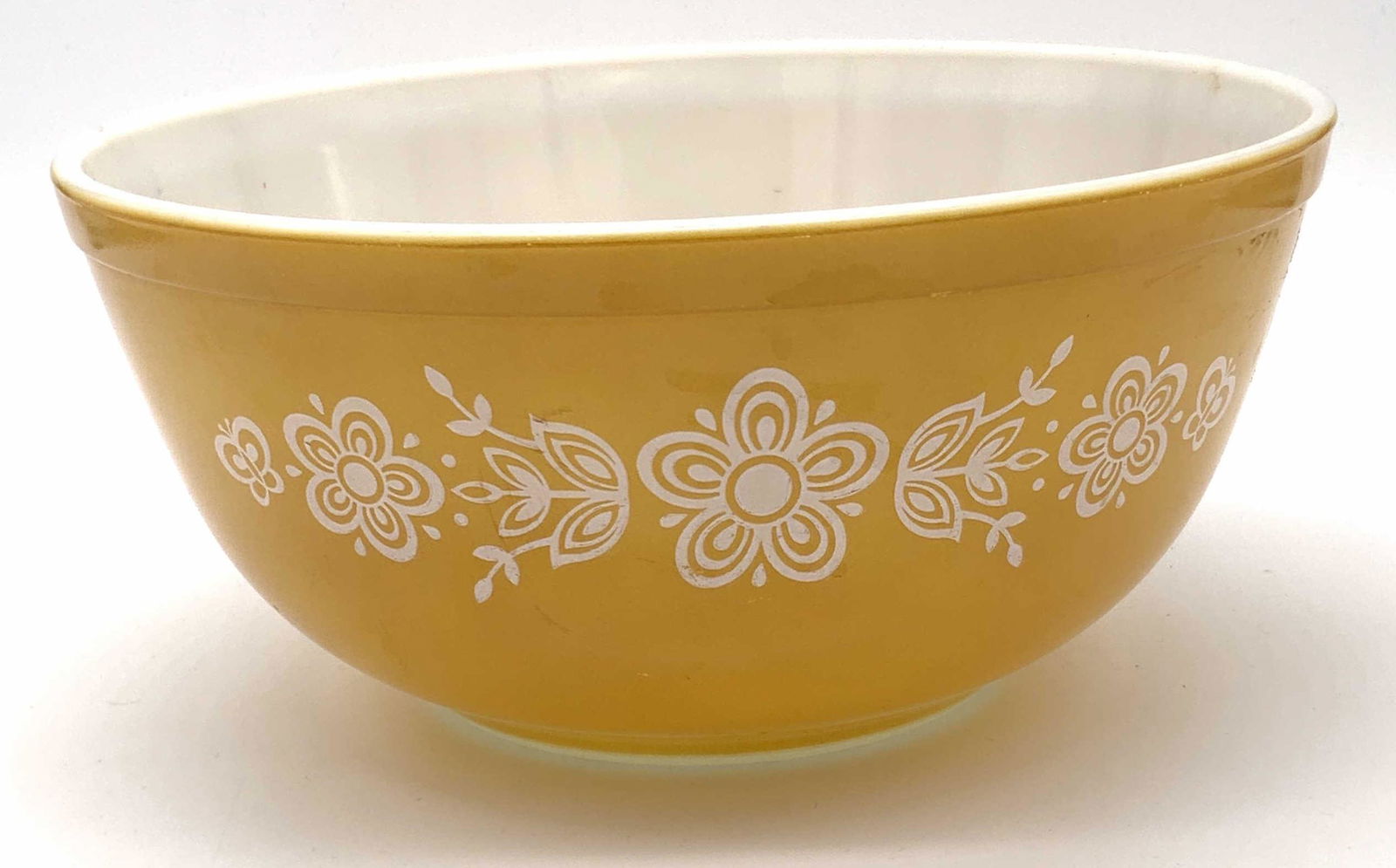 Lot 2 Vintage Trademarked PYREX Daisy Bowls: Two vintage Pyrex bowls. One piece is green hued with airy accents, has handled sides. The yellow bowl also features a daisy pattern. Both undersides read TRADEMARK PYREX, MADE IN USA, OVENWARE. Large