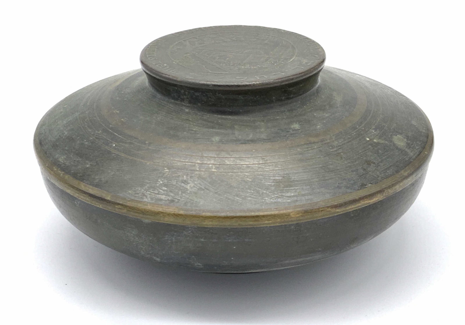 Signed Vintage Lidded Brass Trinket Box, Israel: A vintage lidded metal, possibly brass, trinket box. The piece is circular in shape. The very top of the lid reads RACHEL’S TOMB and features raised and etched metalwork. The underside is signed MAD
