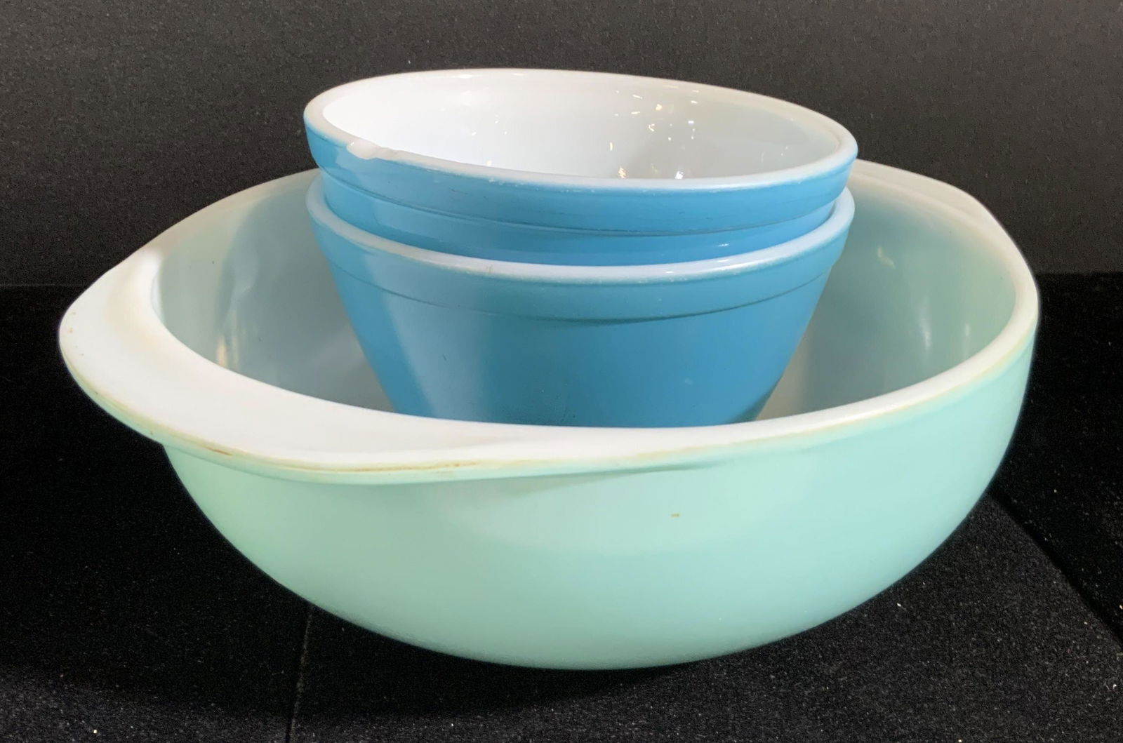 Lot 3 Vintage Trademark PYREX Ovenware Bowls: Three possibly vintage Pyrex bowls. All bowls are various blue hues. Undersides read PYREX, OVENWARE, MADE IN USA. Largest bowl approx. 3H x 10.5W in. Largest bowl is handled. Varying sizes. All piece